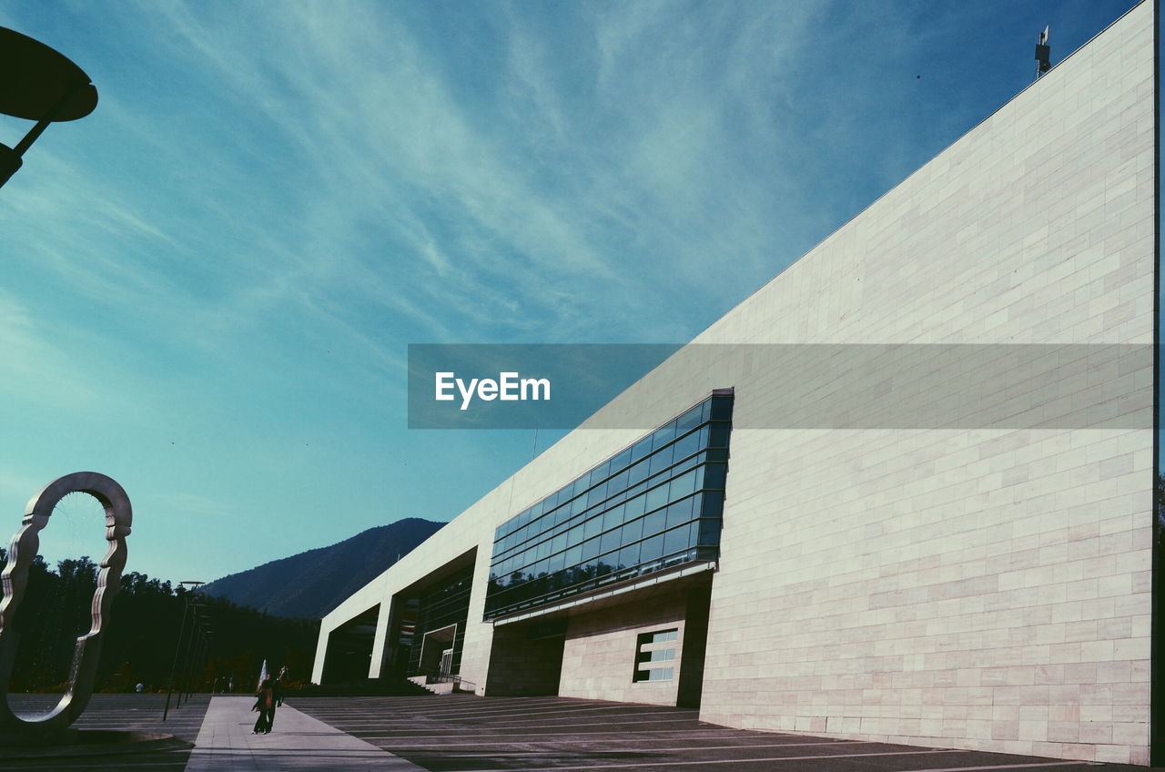 MAN WALKING ON BUILDING AGAINST SKY