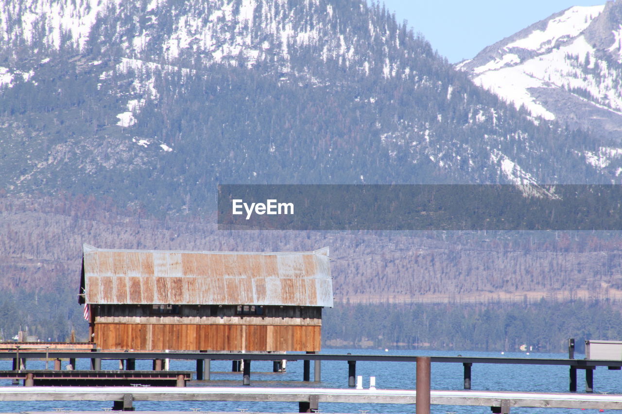 Built structure by sea against sky during winter