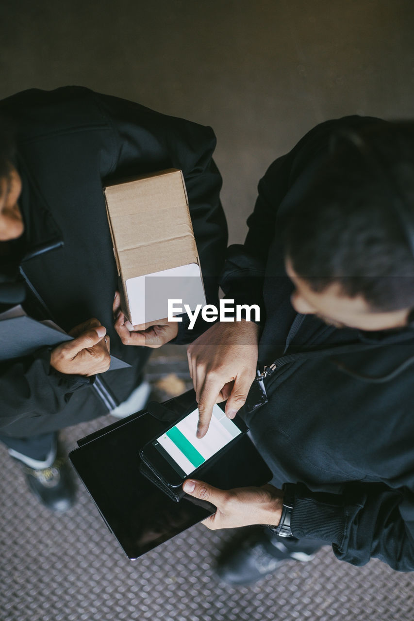 Female and male manual workers using mobile phone at warehouse