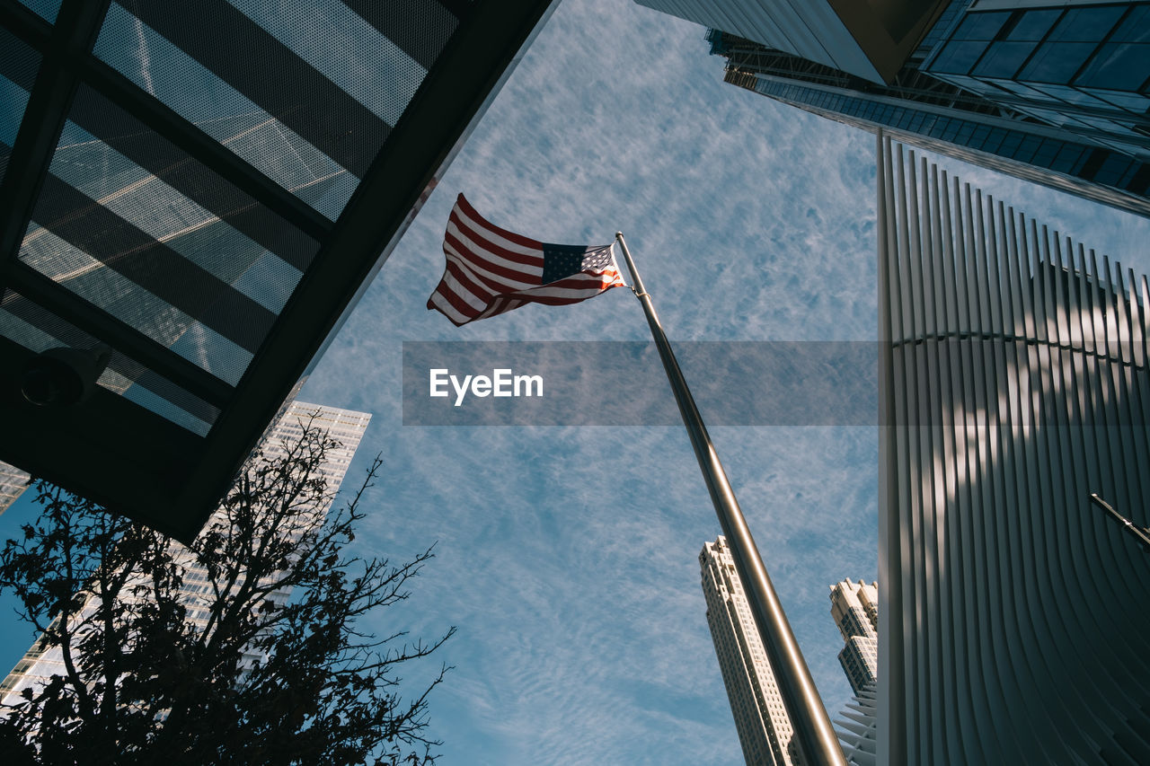 LOW ANGLE VIEW OF FLAGS HANGING AGAINST BUILDINGS