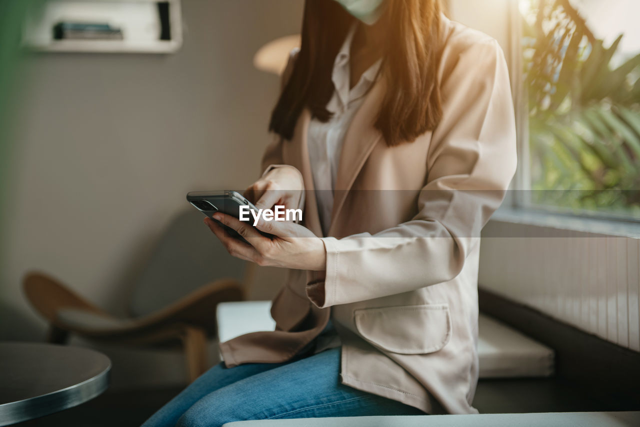 midsection of woman using smart phone