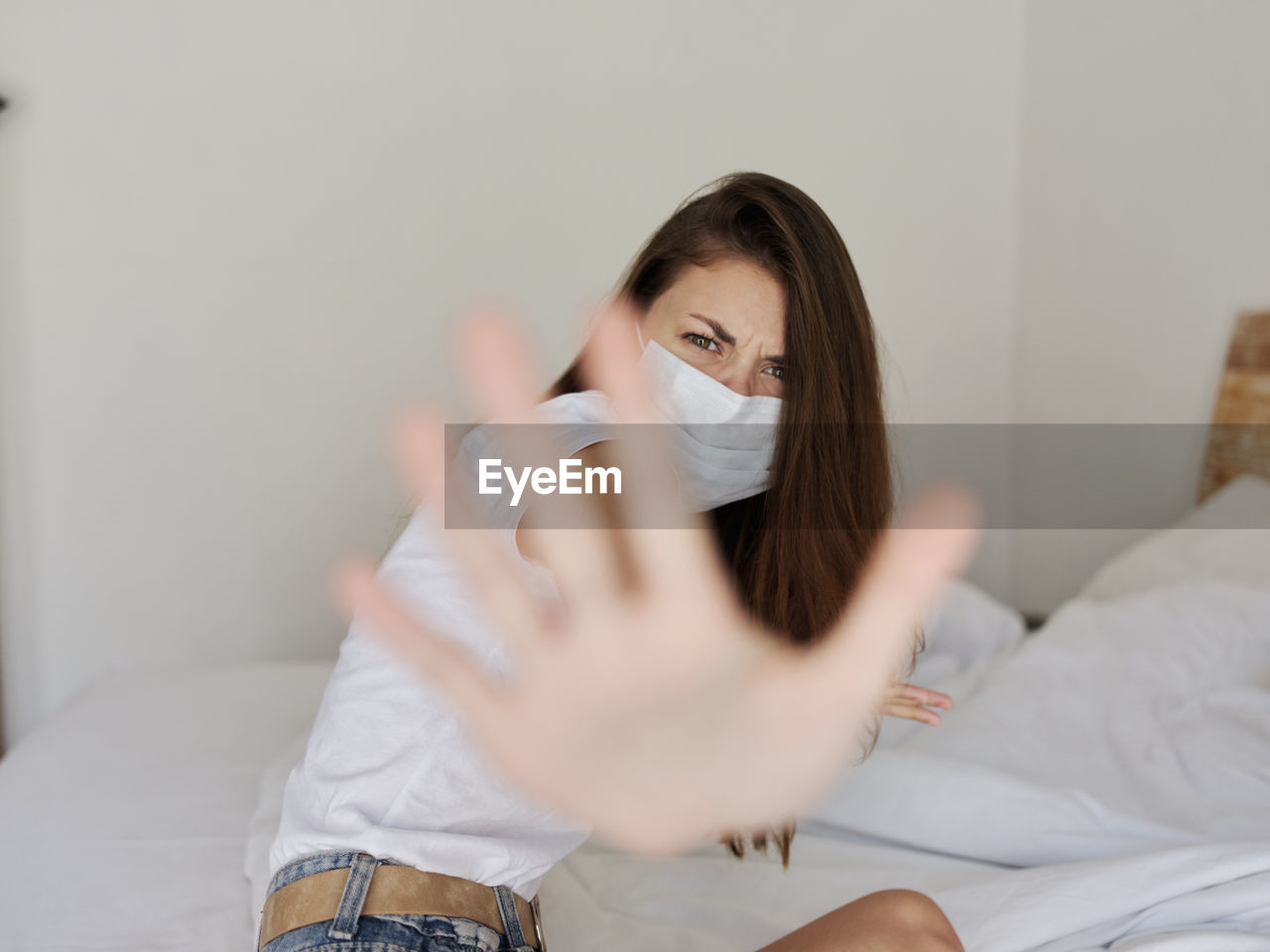 PORTRAIT OF YOUNG WOMAN SITTING ON BED