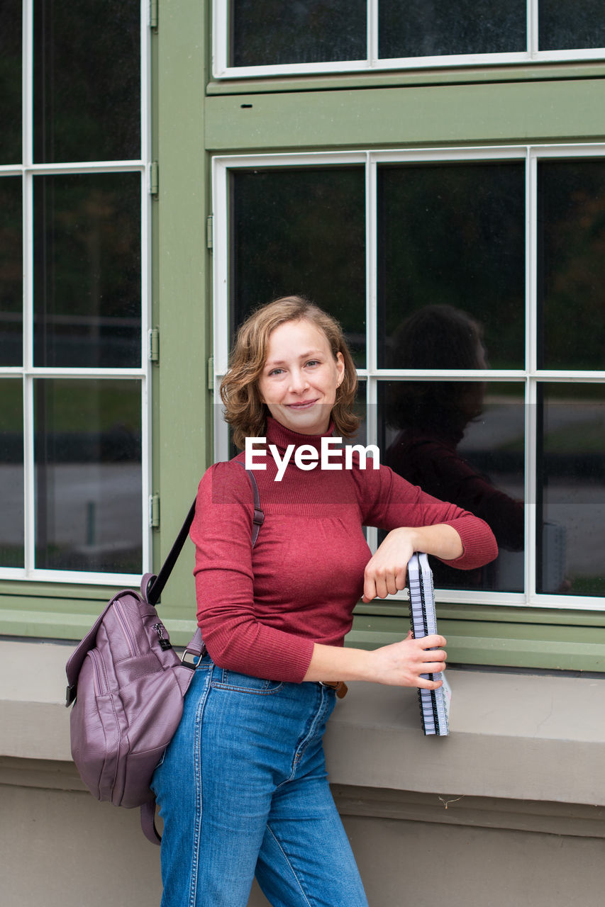 Young caucasian girl going back to college, school, standing with a notebooks