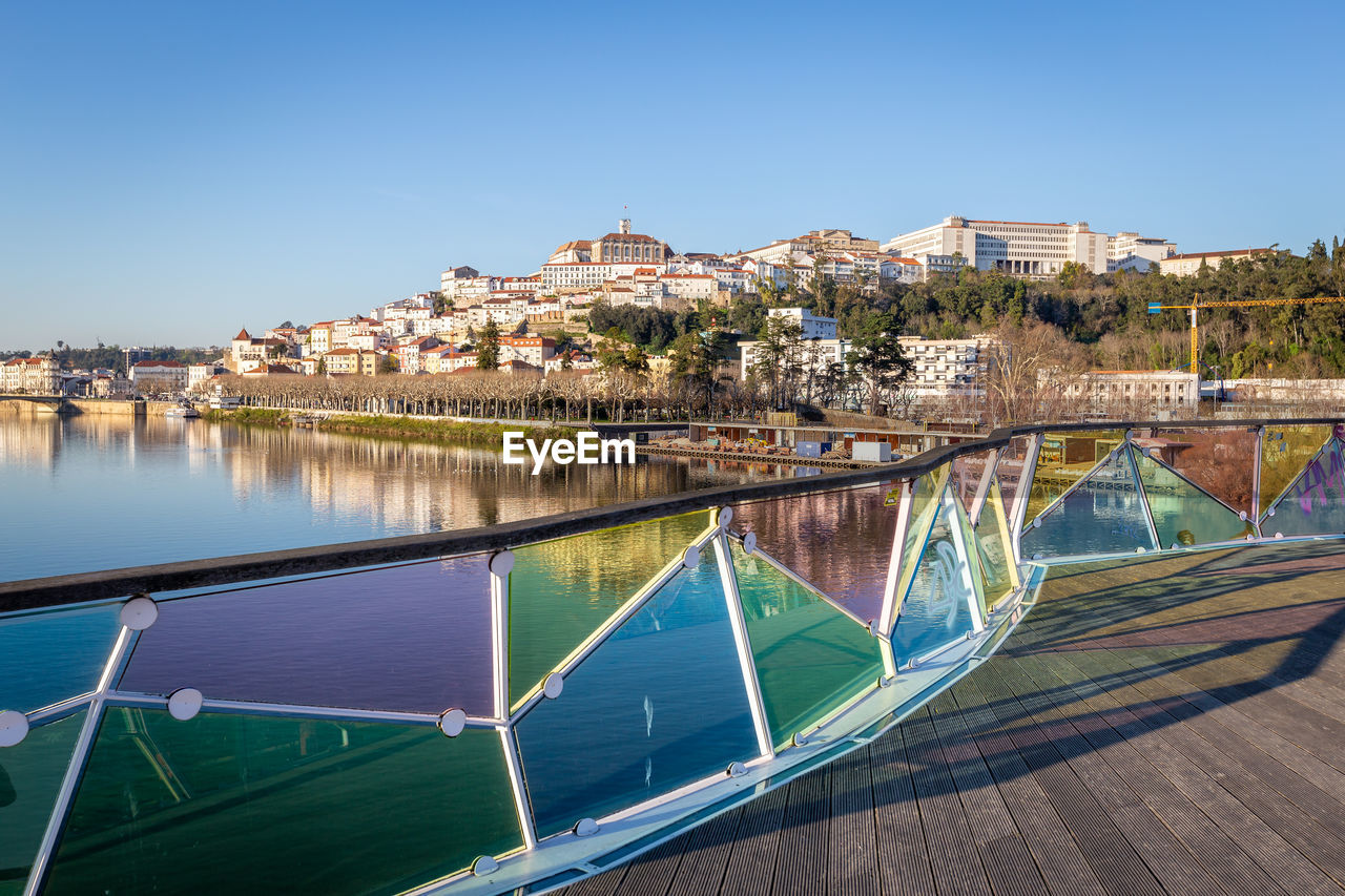 AERIAL VIEW OF TOWNSCAPE BY RIVER AGAINST CLEAR SKY