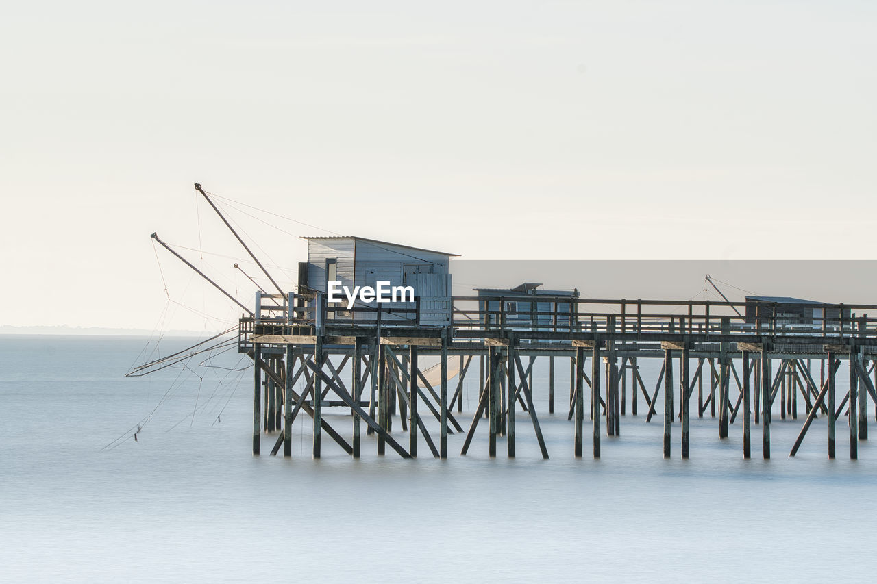 water, sea, pier, architecture, built structure, sky, nature, ocean, no people, horizon over water, stilt house, copy space, coast, beach, horizon, day, tranquility, scenics - nature, outdoors, beauty in nature, wood, building exterior, building, vehicle, land, tranquil scene, hut, shore