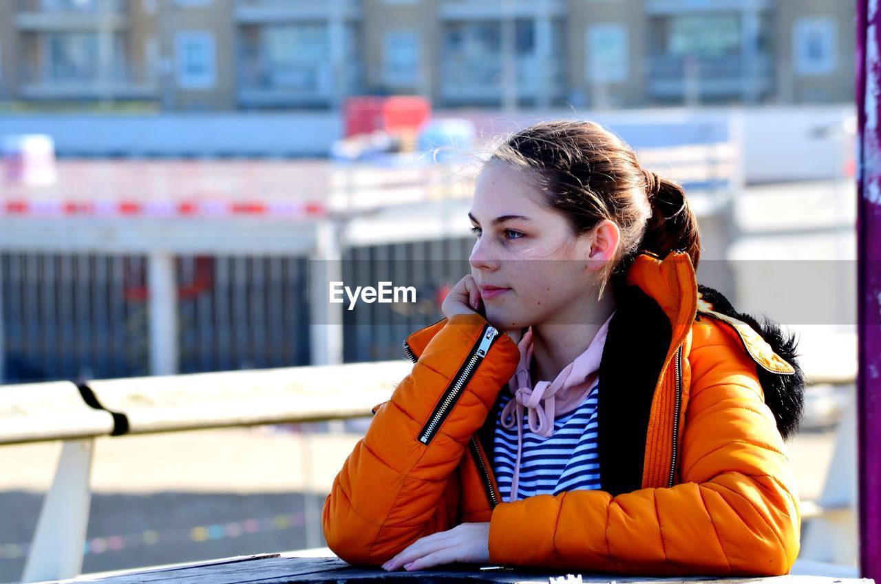 Portrait of young woman looking away while sitting in winter