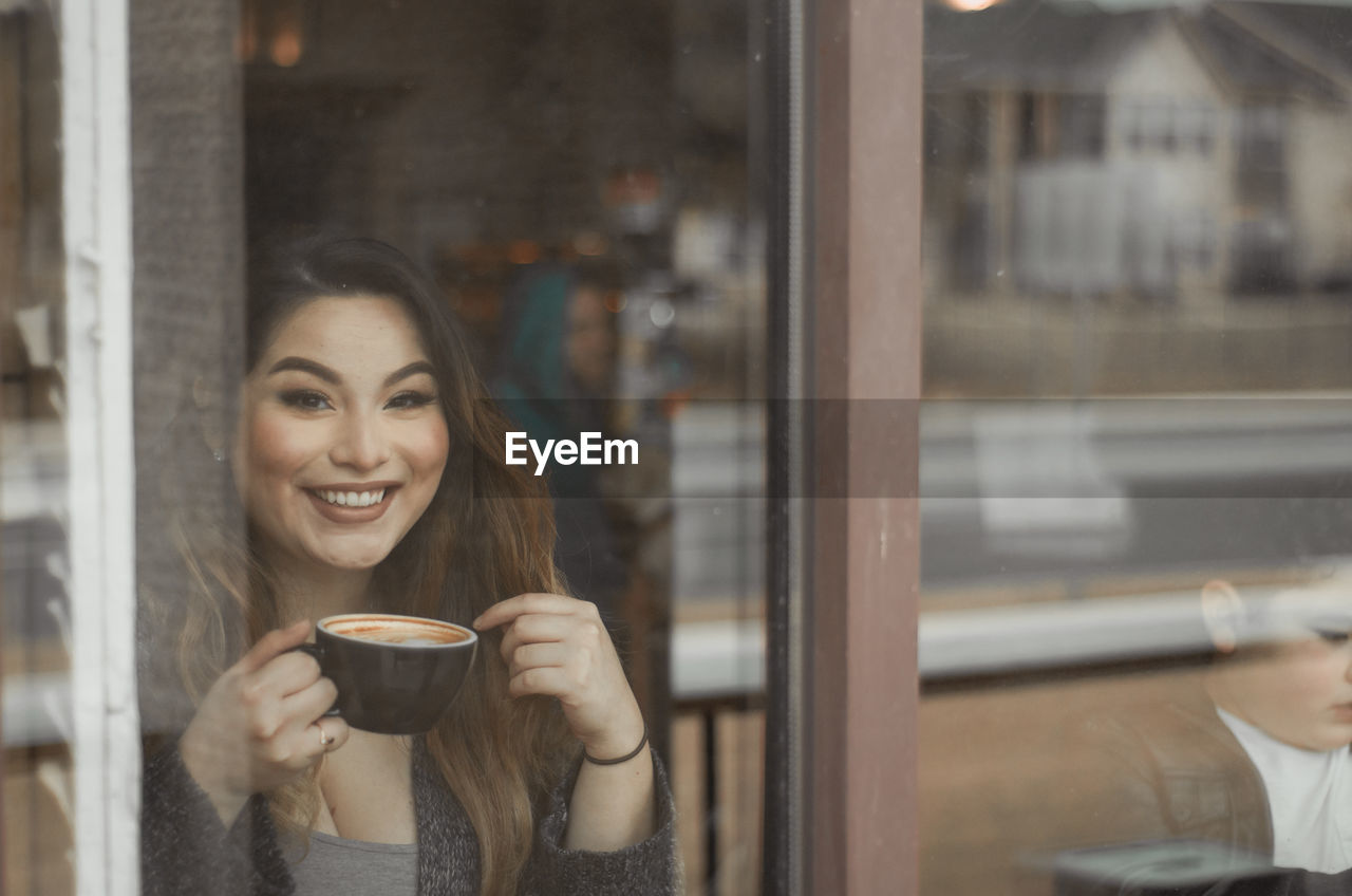 Portrait of young woman holding coffee in cafe