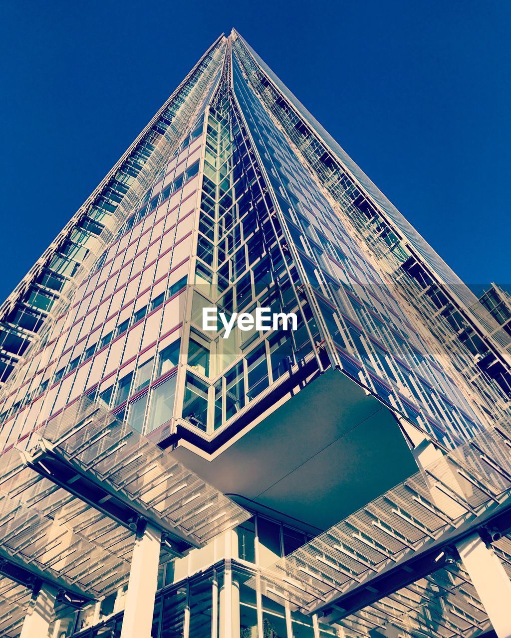 LOW ANGLE VIEW OF MODERN SKYSCRAPER AGAINST BLUE SKY