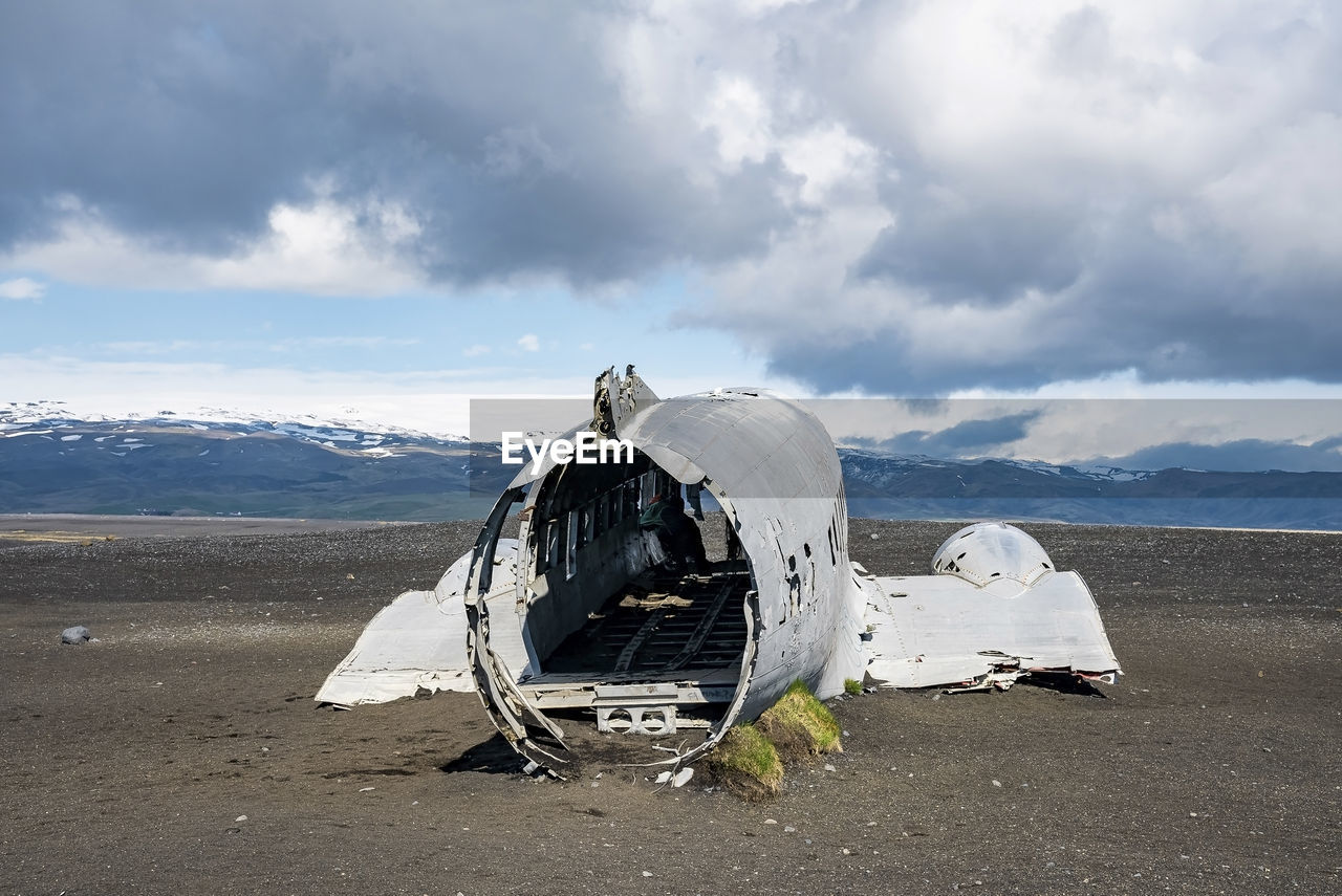 Broken airplane wreck at black sand beach in solheimasandur against cloudy sky