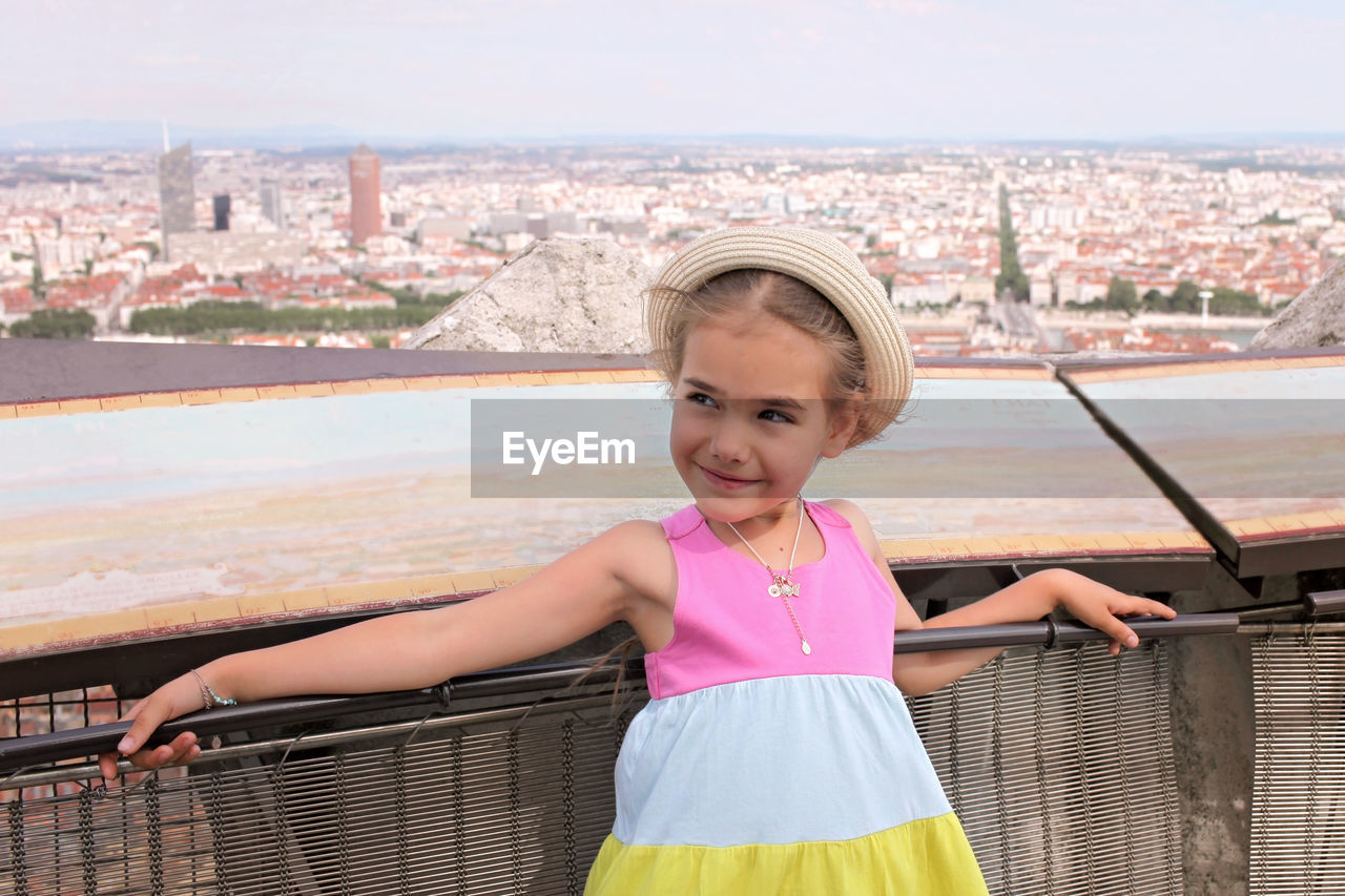 PORTRAIT OF SMILING GIRL STANDING BY RAILING