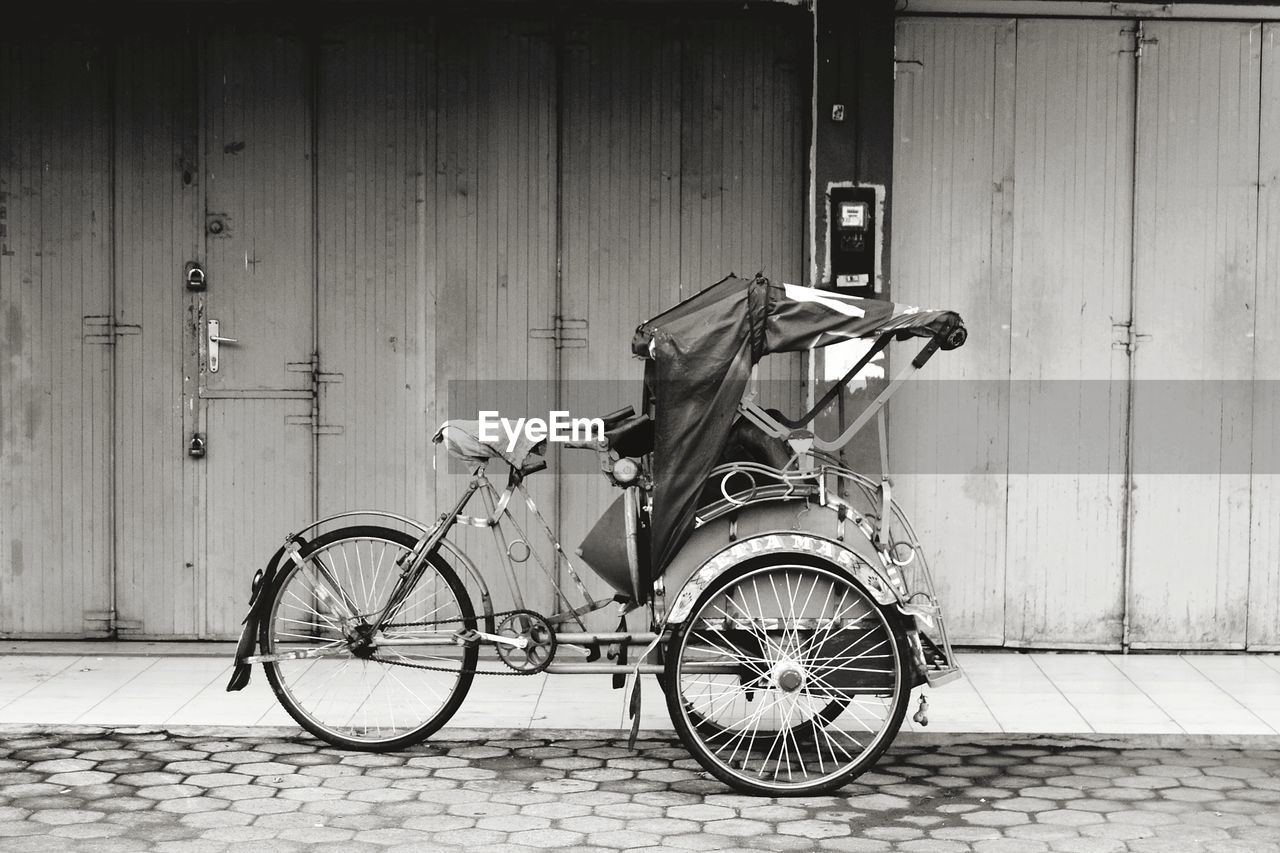 Bicycle parked on footpath against house