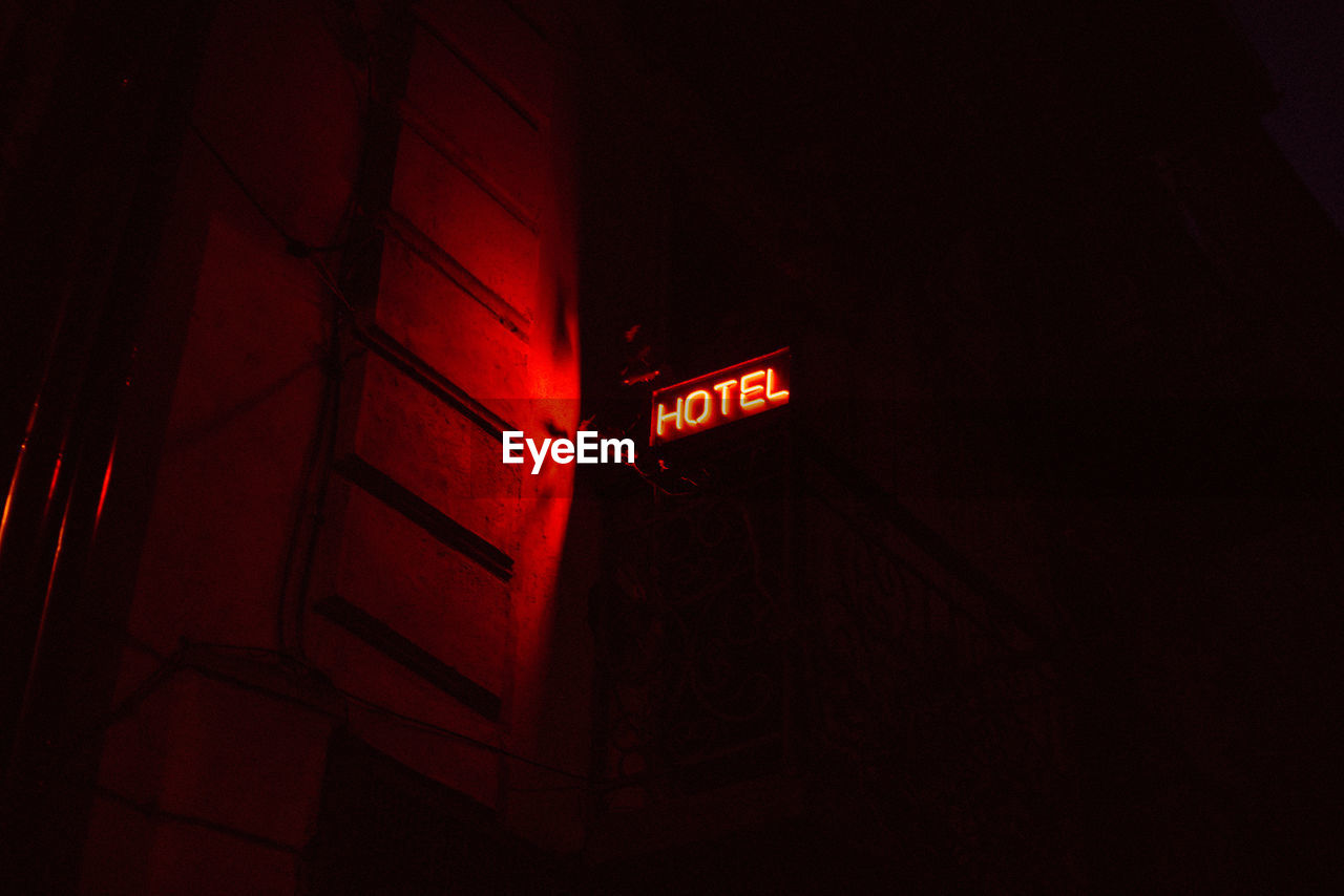 Low angle view of illuminated hotel sign on building at night