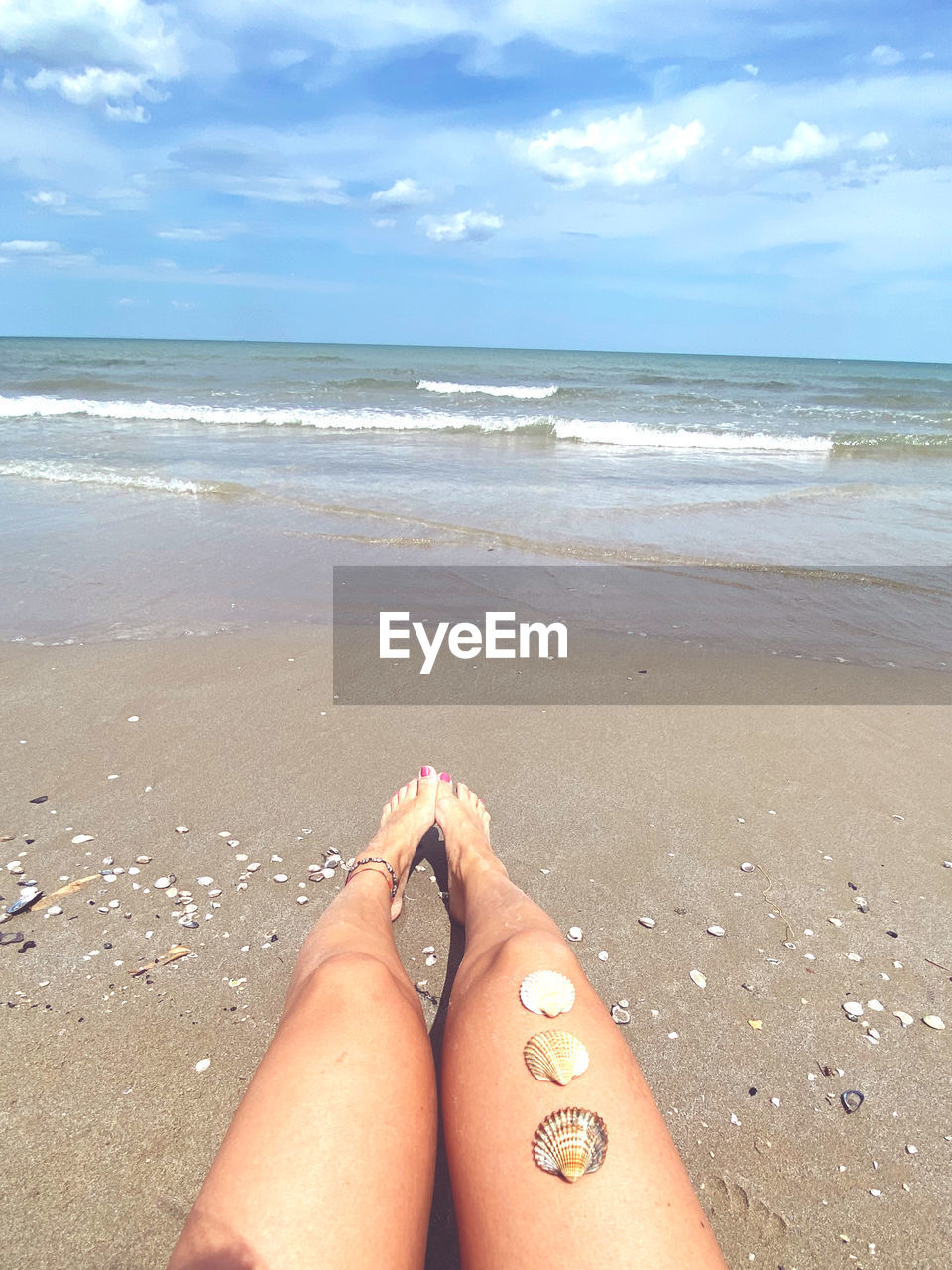 LOW SECTION OF WOMAN RELAXING ON BEACH