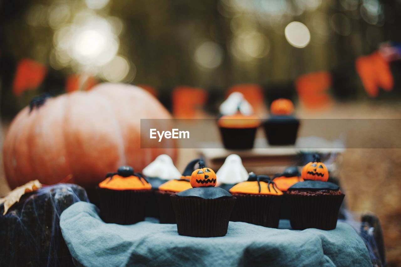 Close-up of cupcakes and pumpkin on table during halloween celebration