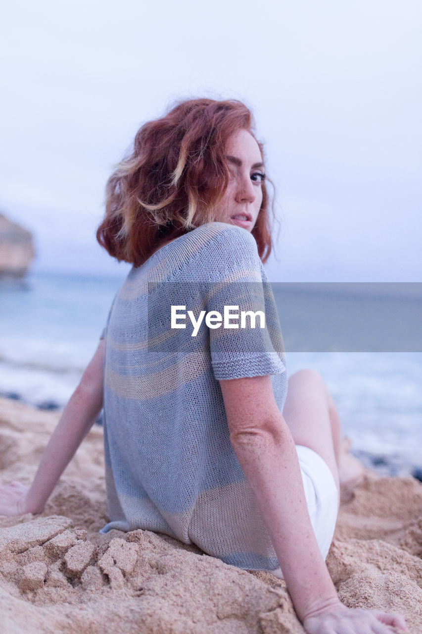 Rear view portrait of woman sitting at beach