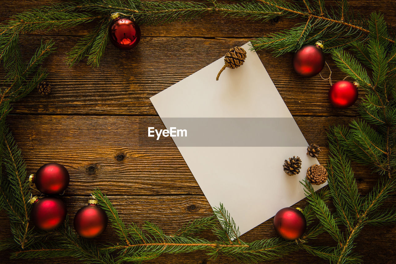 High angle view of pine needles with blank paper on wooden table