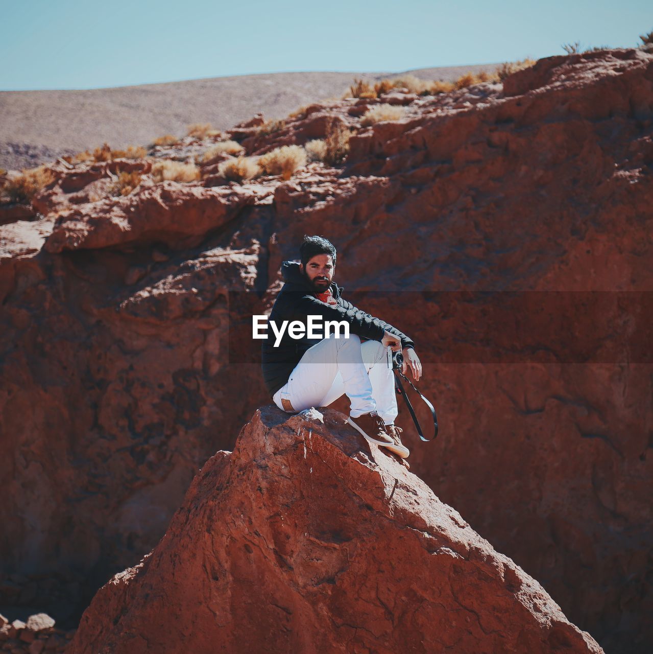 Portrait of man sitting on rock formation during sunny day