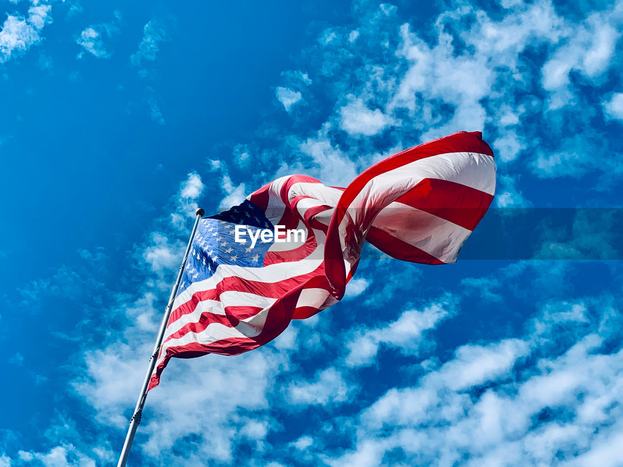 Low angle view of american flag against blue sky