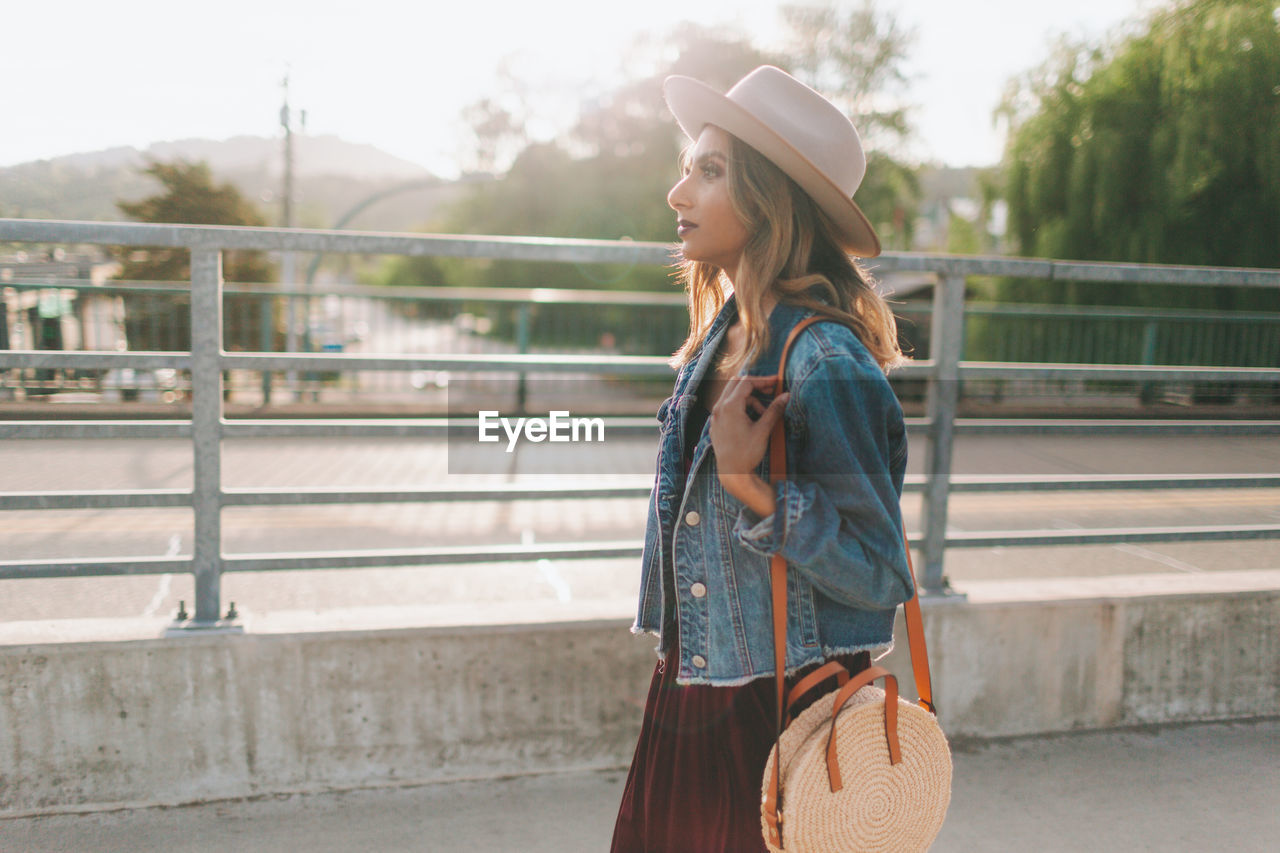 Side view of woman carrying purse while walking on street