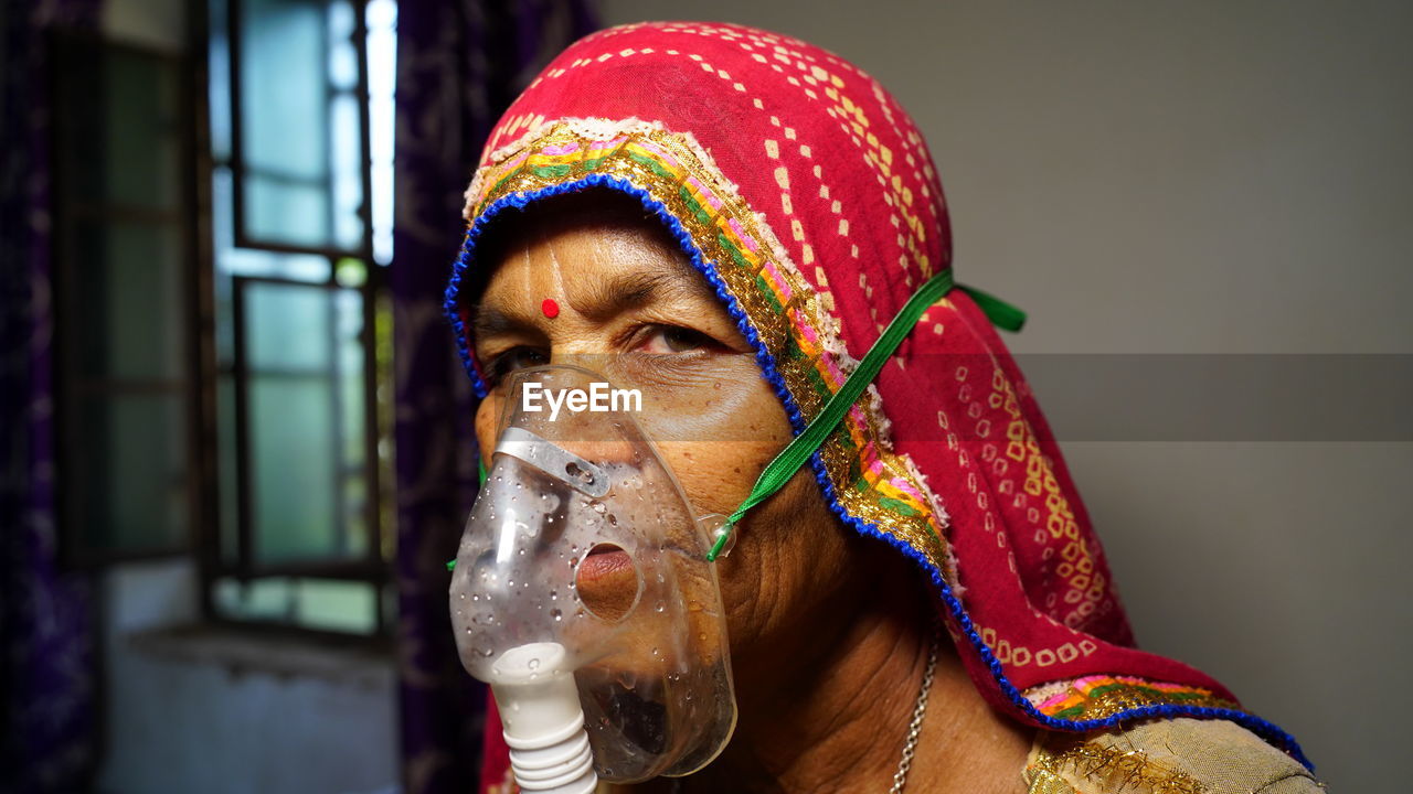 Close-up portrait of woman wearing oxygen mask at home