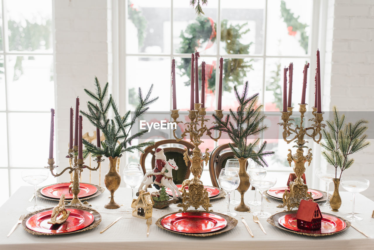 Christmas serving of a festive new year's dinner. candles in candlesticks, spruce branches, red 