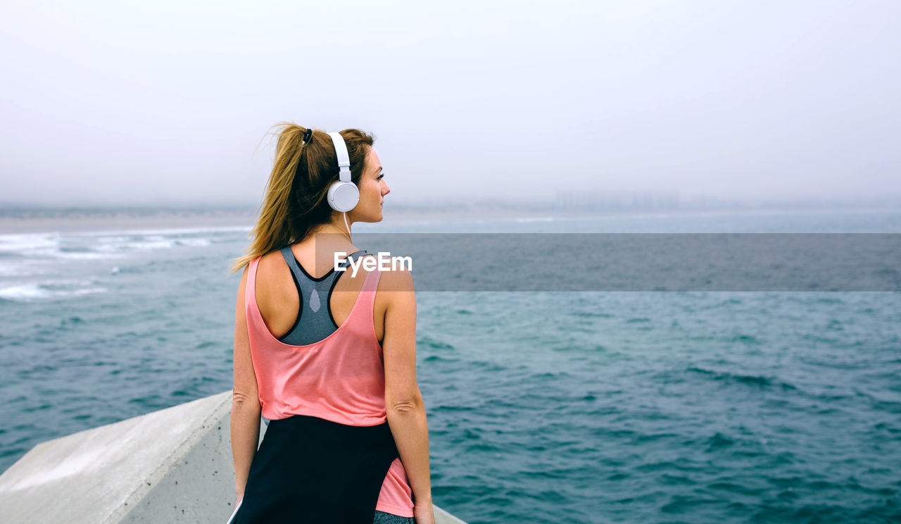 Woman standing on pier against sky