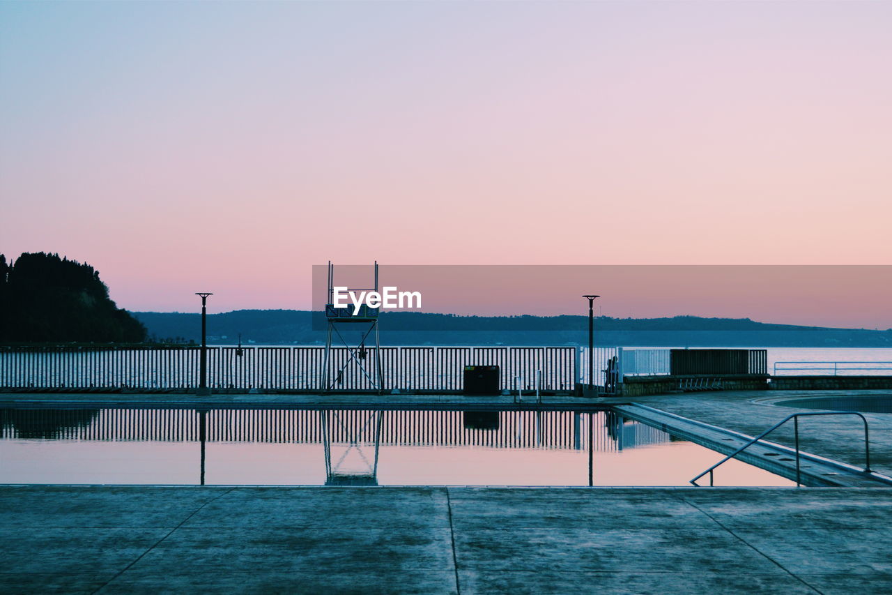 Swimming pool against sky during sunset