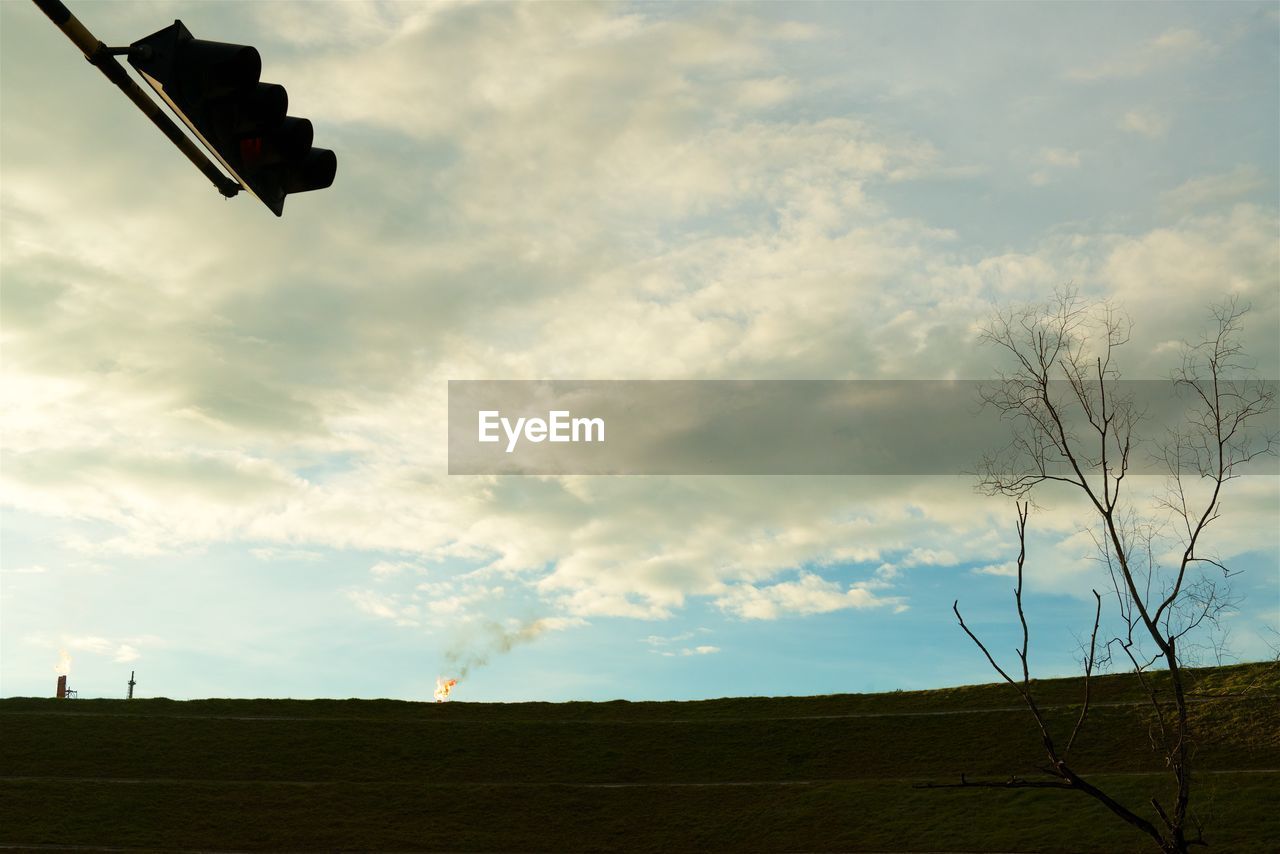 Traffic light on landscape against sky