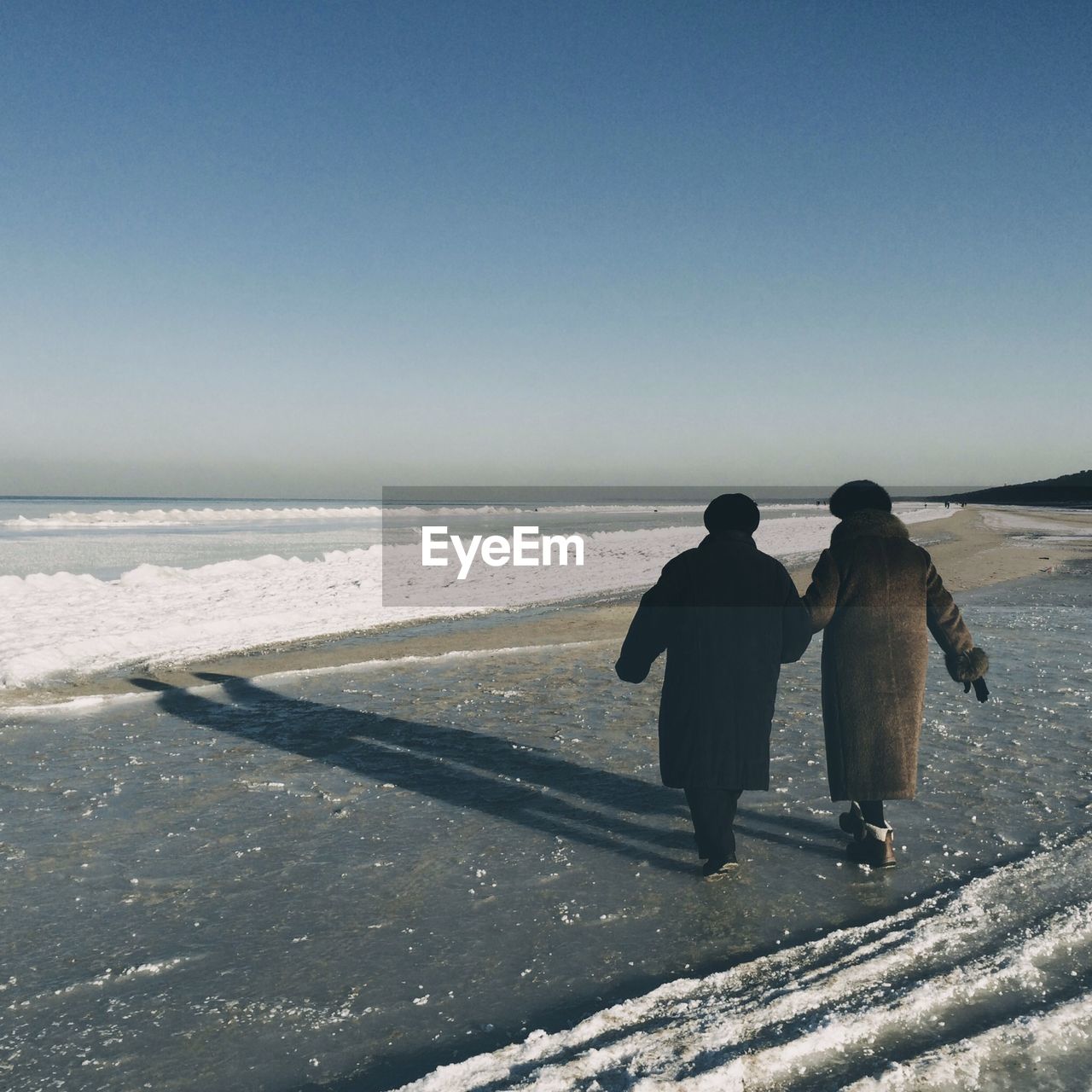 Rear view of couple walking on beach