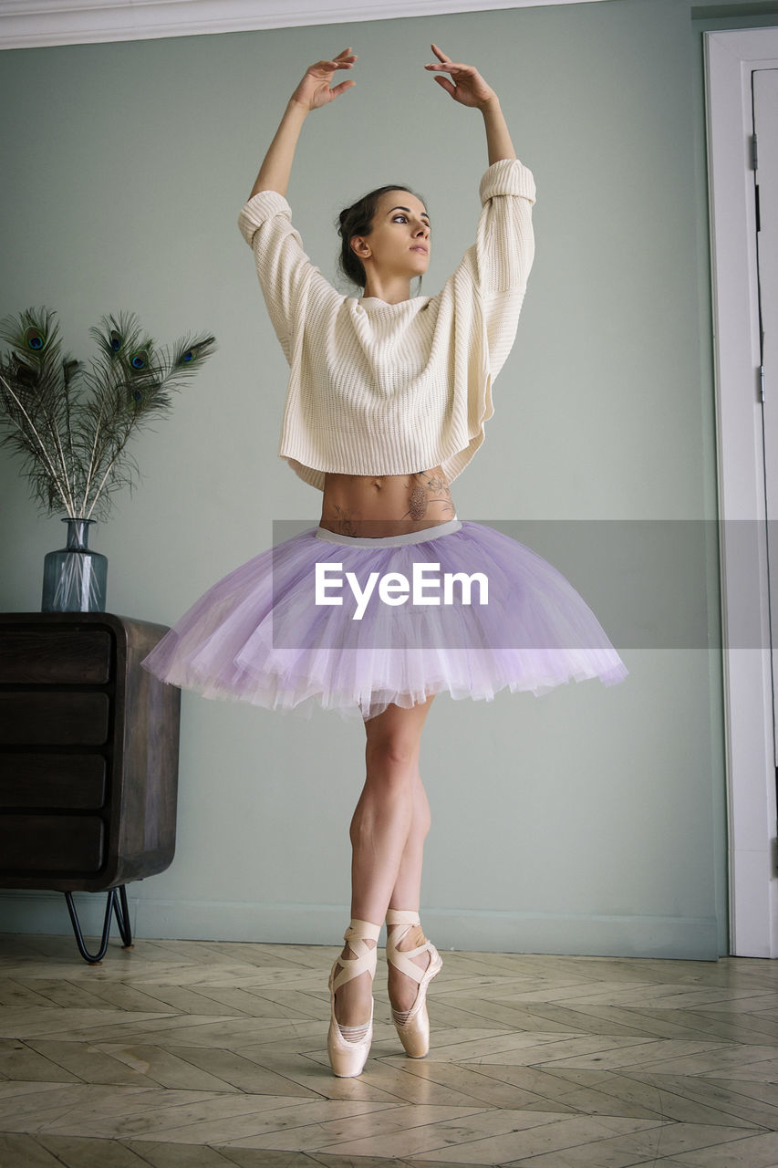 ballet tutu, ballet, ballet dancer, dancing, dance skirt, performing arts, full length, tutu, indoors, one person, women, skill, limb, entertainment, standing, arm, human limb, elegance, balance, performance, female, sports, skirt, arms raised, team sport, child, event, ballet shoe, adult, front view, shoe, performing arts event, young adult, portrait, childhood, arts culture and entertainment, fashion, footwear, leotard, clothing, person, costume, lifestyles, flexibility, practicing