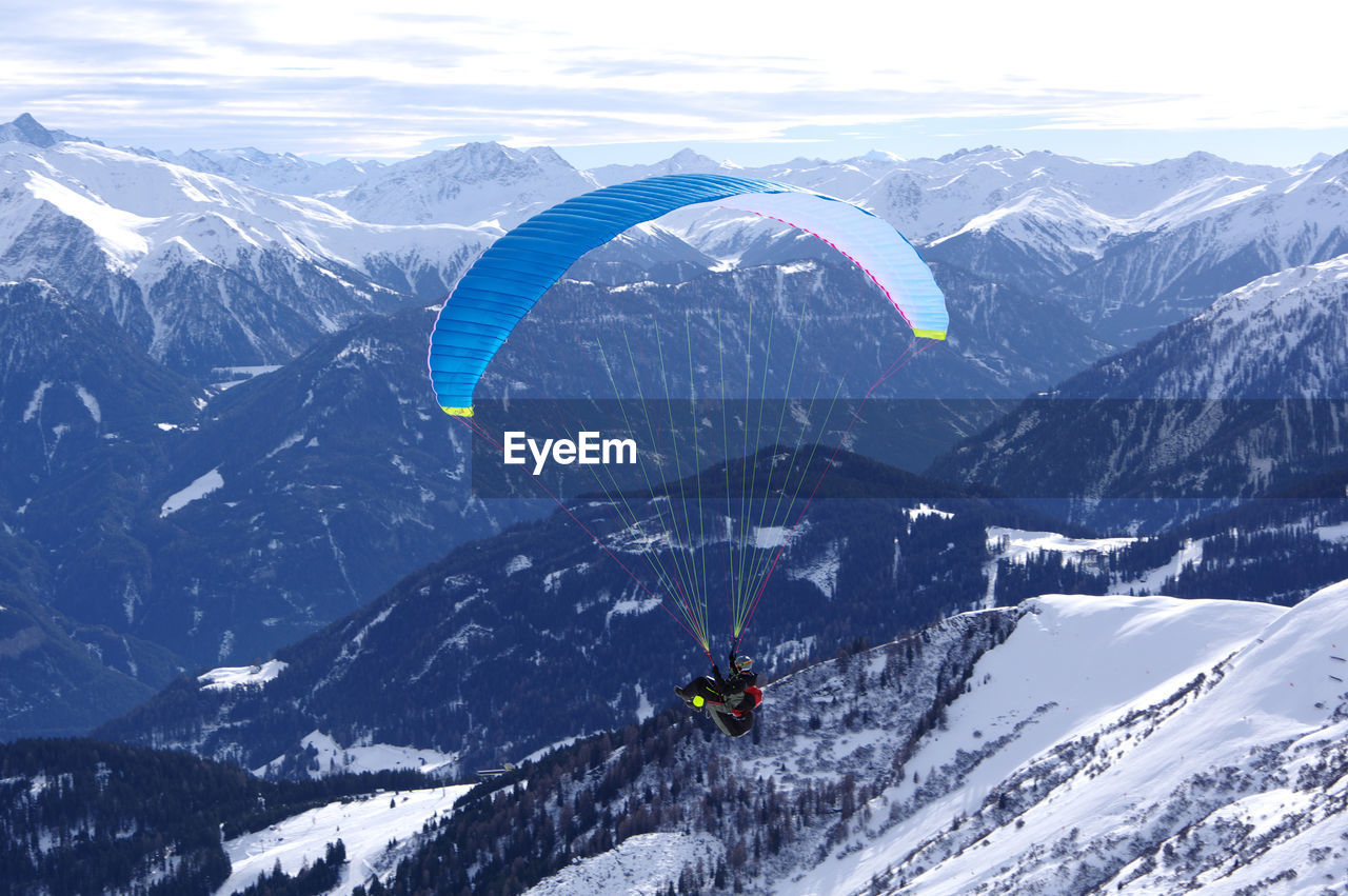 Man paragliding over snowcapped mountains