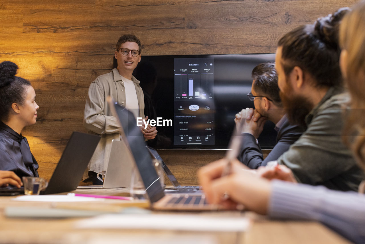 Confident businessman giving presentation to colleagues during meeting in board room