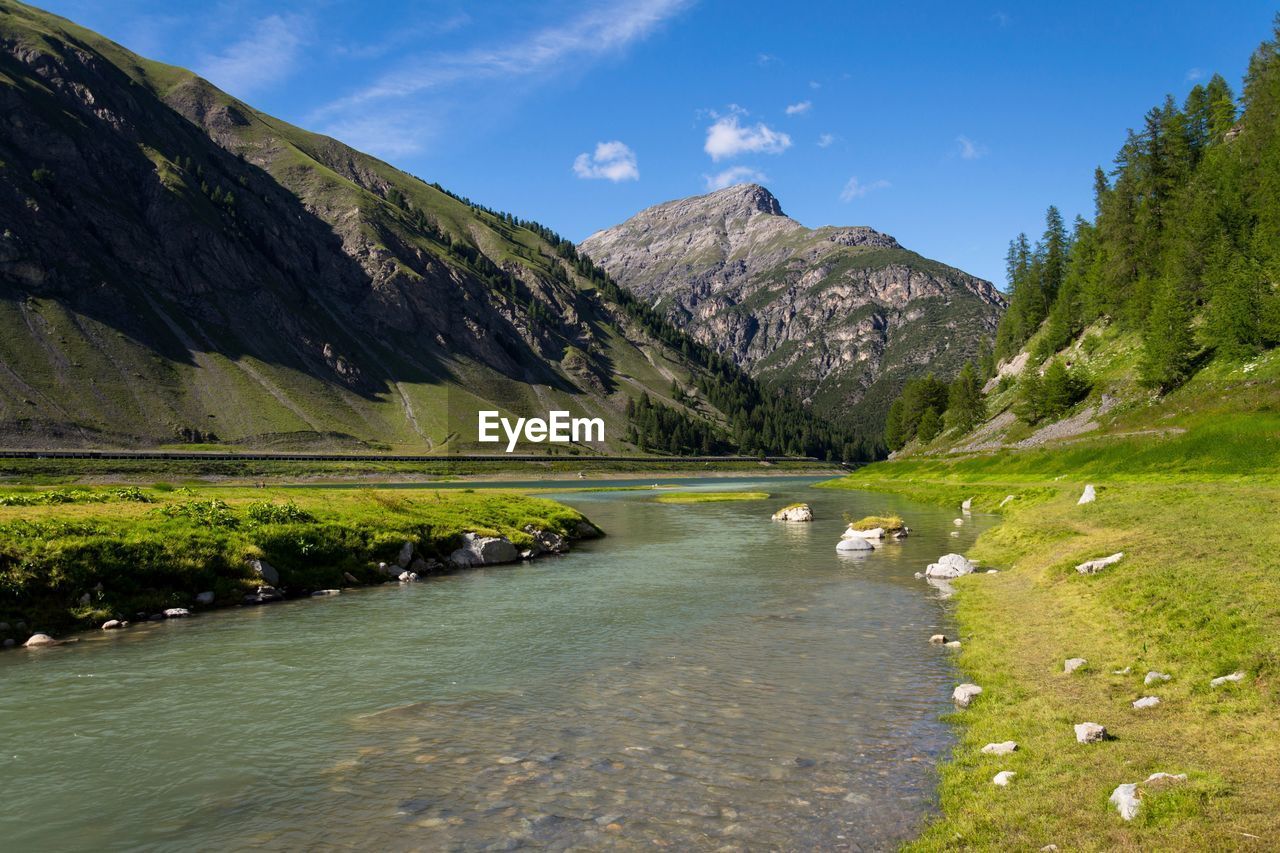 scenic view of river amidst mountains against sky