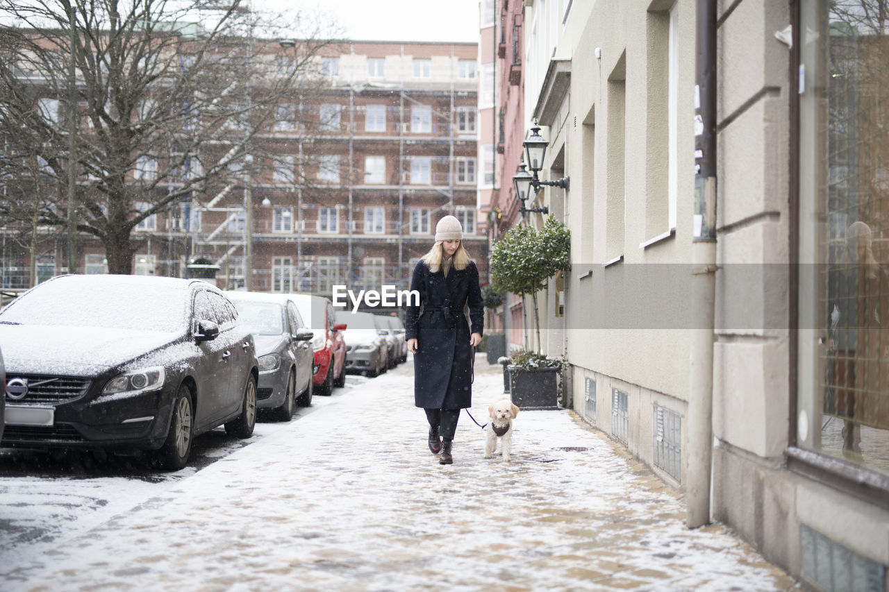 Woman with dog walking on winter street