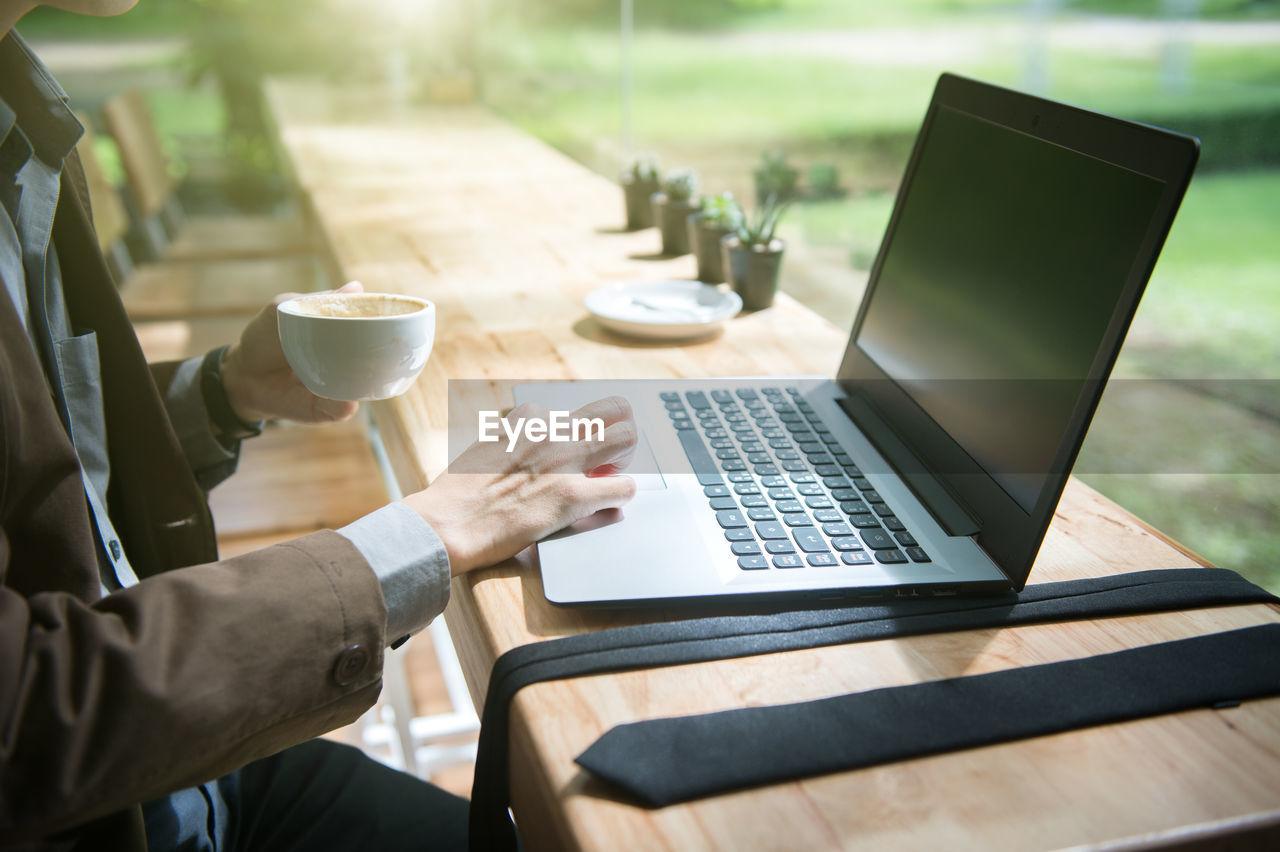 MIDSECTION OF MAN USING LAPTOP