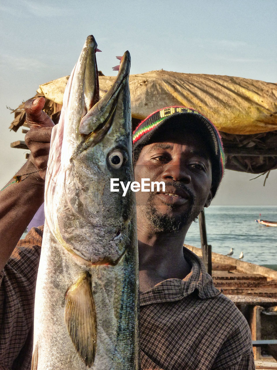 fish, real people, one person, leisure activity, casual clothing, fisherman, seafood, lifestyles, one animal, sea, beach, outdoors, day, nautical vessel, men, young adult, one man only, only men, adult, people