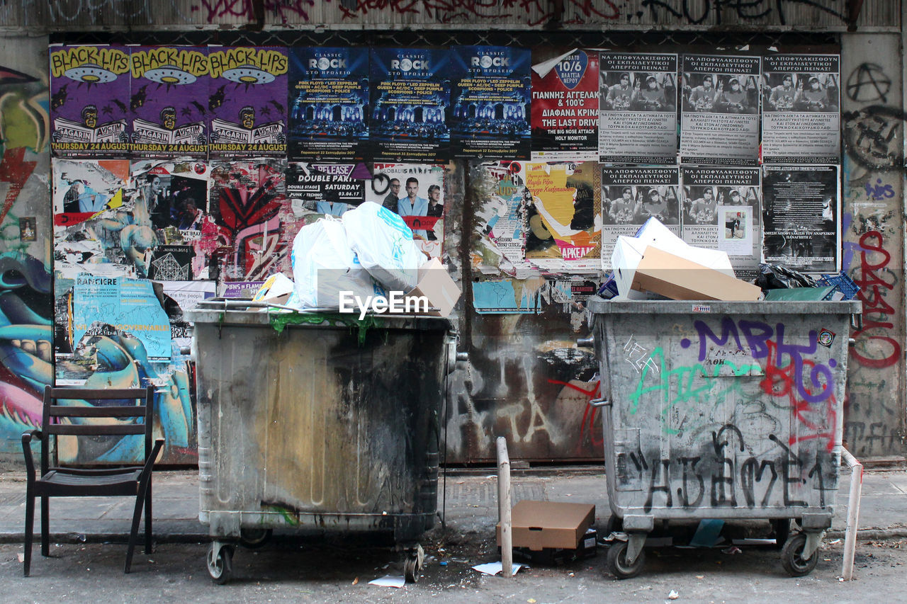 Garbage cans on street against wall