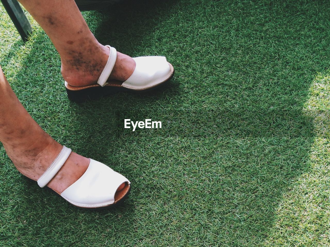 Close-up of woman with dirty legs wearing shoes on grass