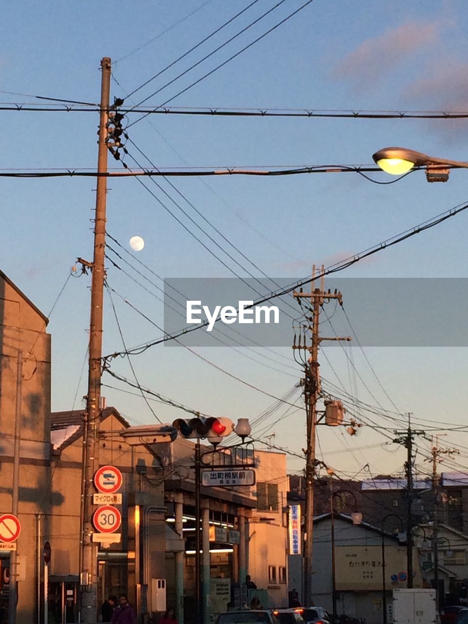 Electricity pylon and stoplight against sky