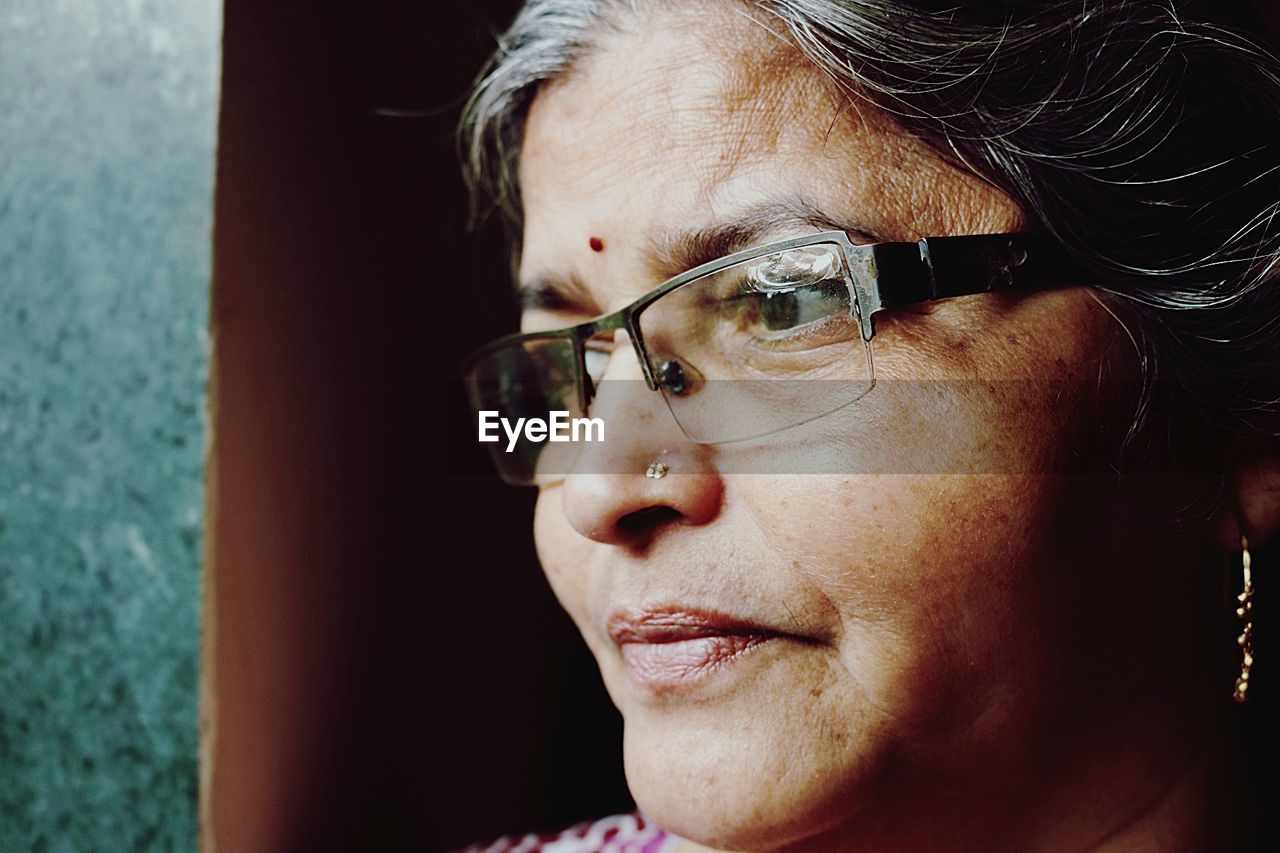 Close-up of thoughtful mature woman looking away by wall