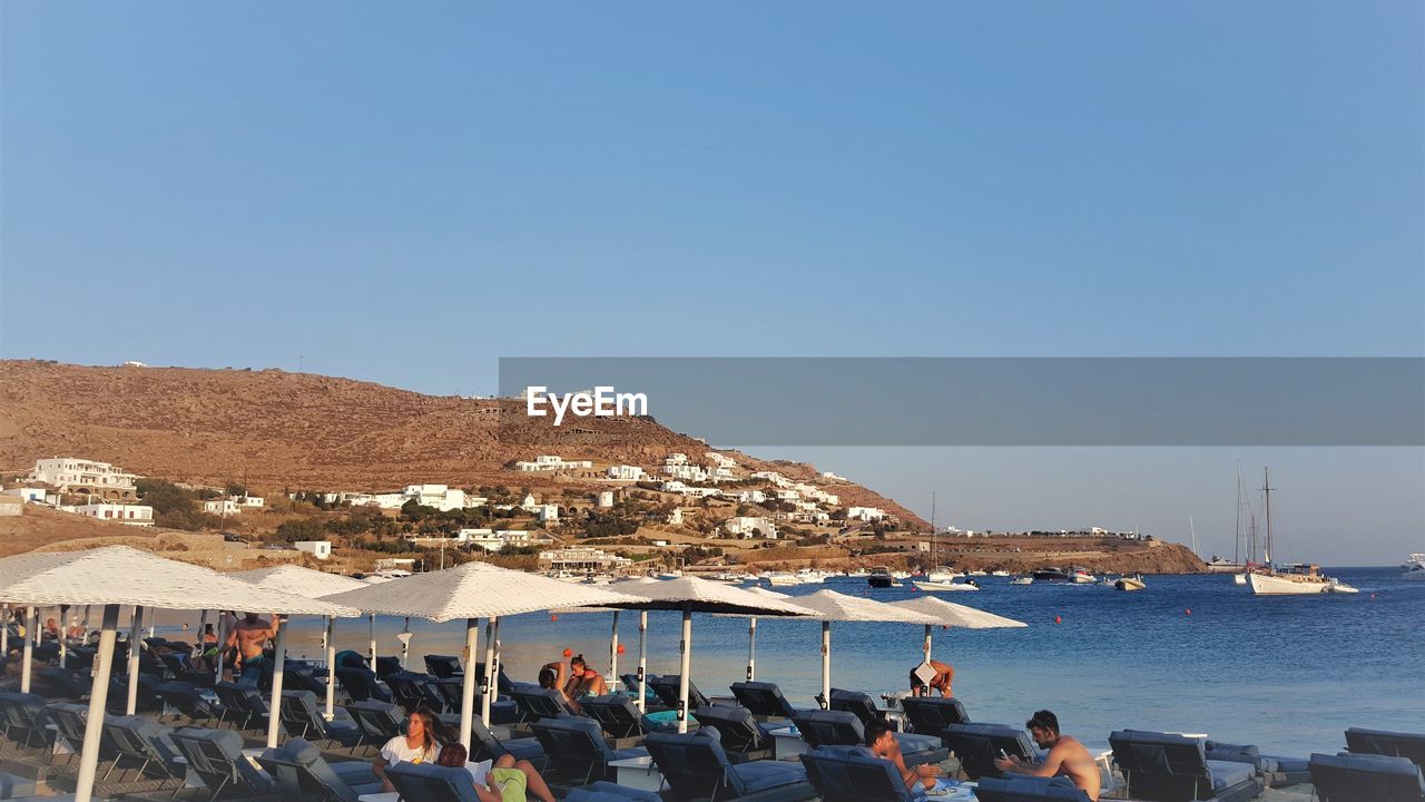 PEOPLE ON BEACH AGAINST CLEAR SKY