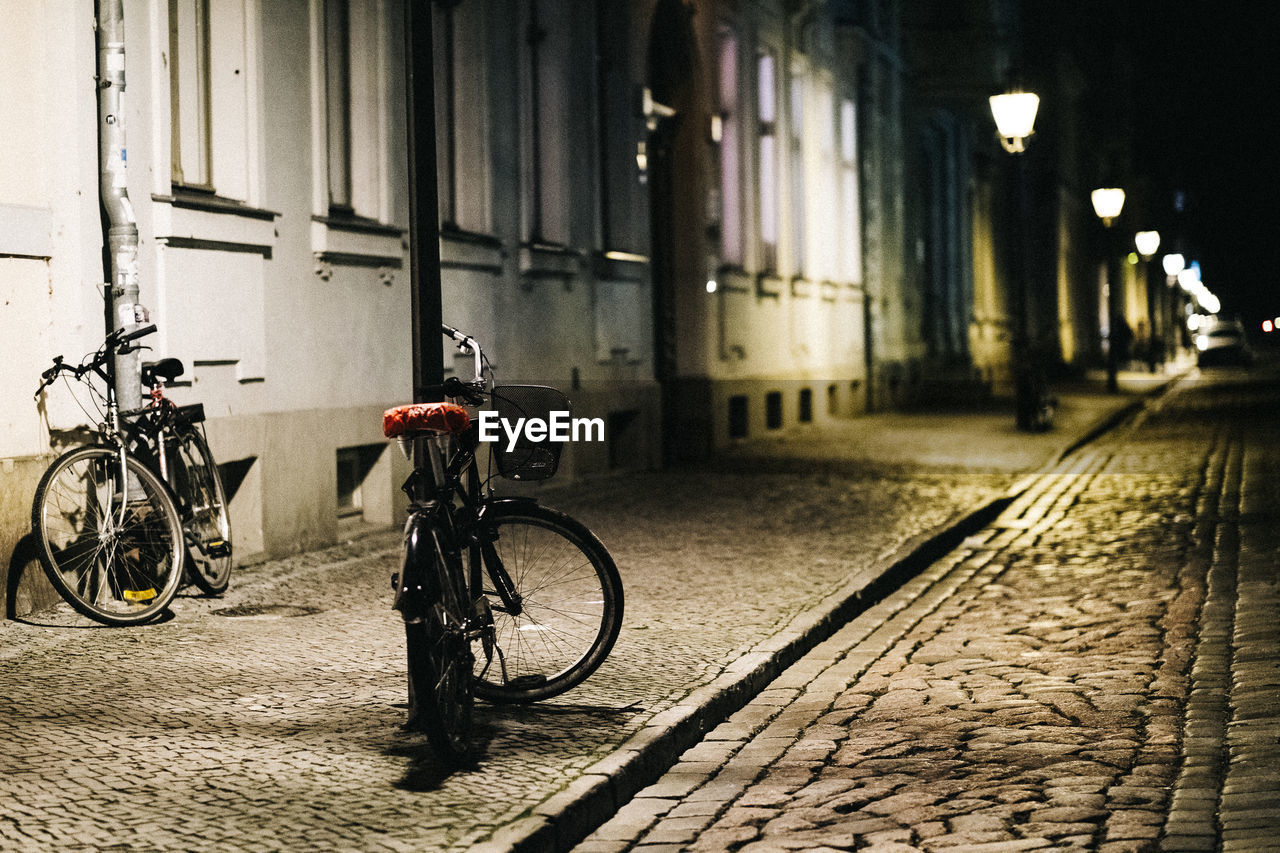 BICYCLE PARKED ON SIDEWALK BY STREET AGAINST BUILDING