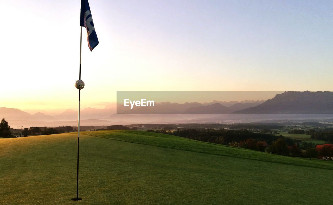 Flag on golf course at sunset