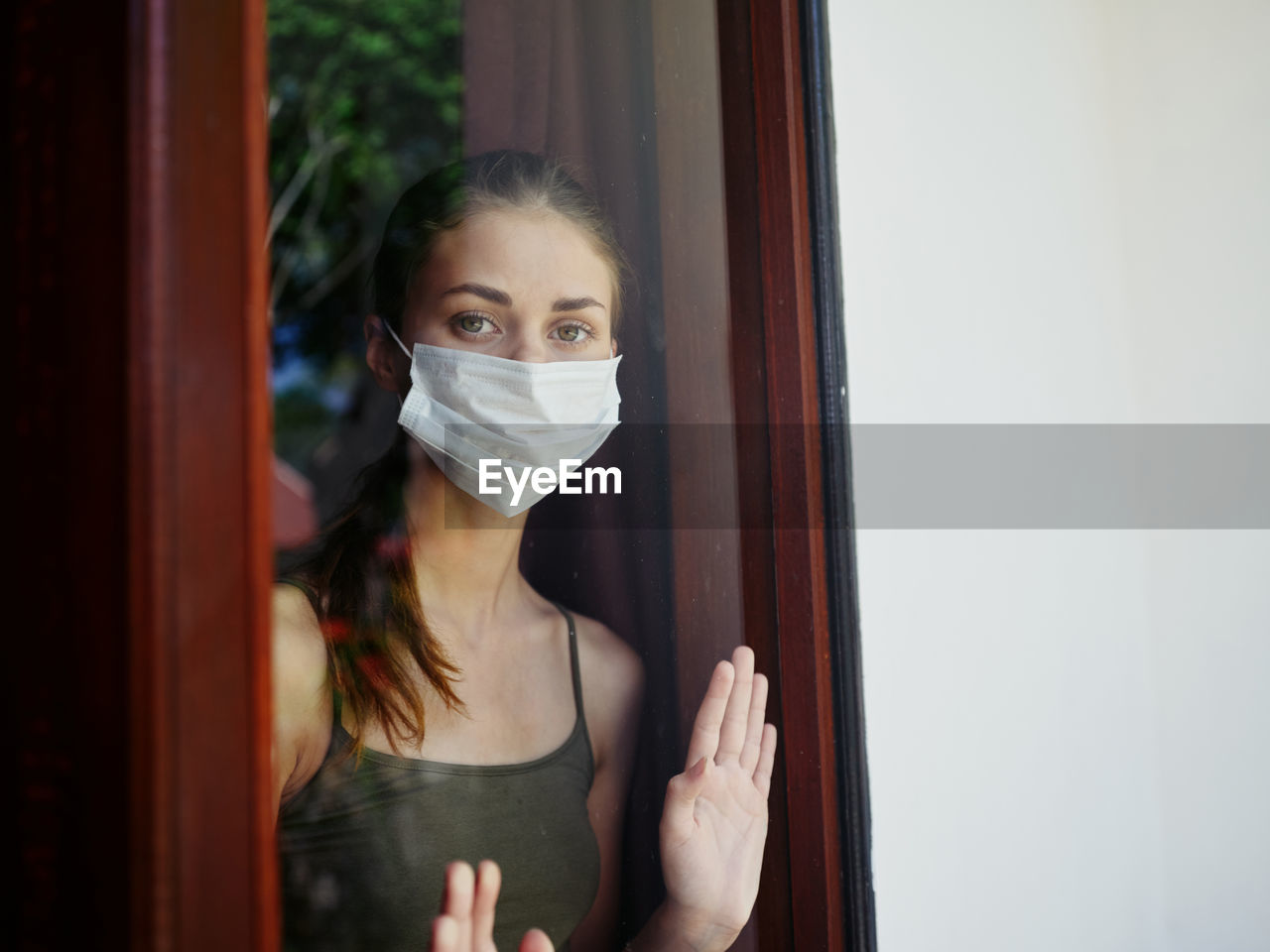 Portrait of young woman standing against door