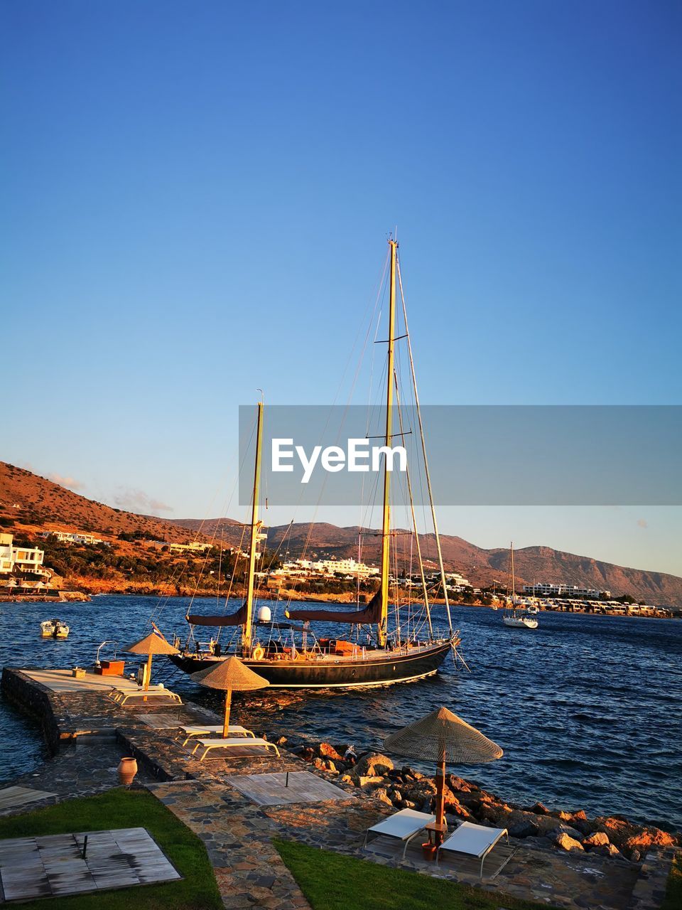 SAILBOAT MOORED IN SEA AGAINST CLEAR BLUE SKY