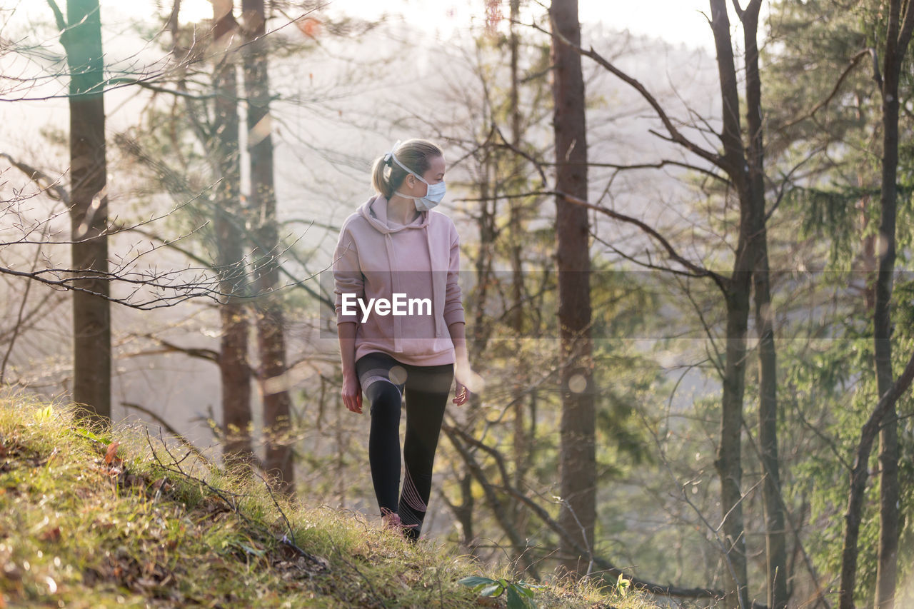 FULL LENGTH OF WOMAN STANDING AMIDST TREES