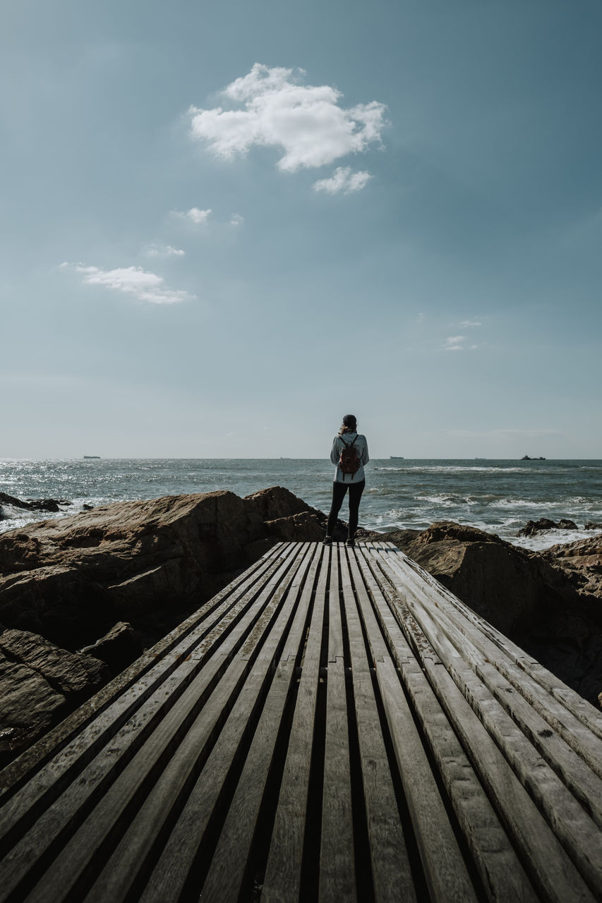 Woman standing on beach against sky