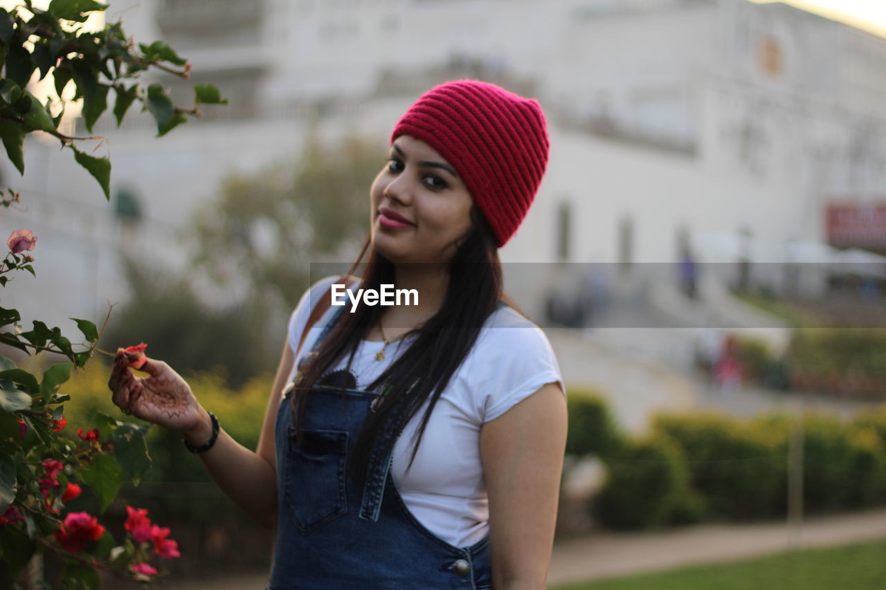 Portrait of woman picking flowers from plant during sunset