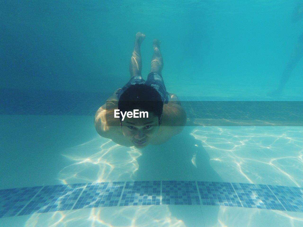 Full length portrait of young man swimming in pool