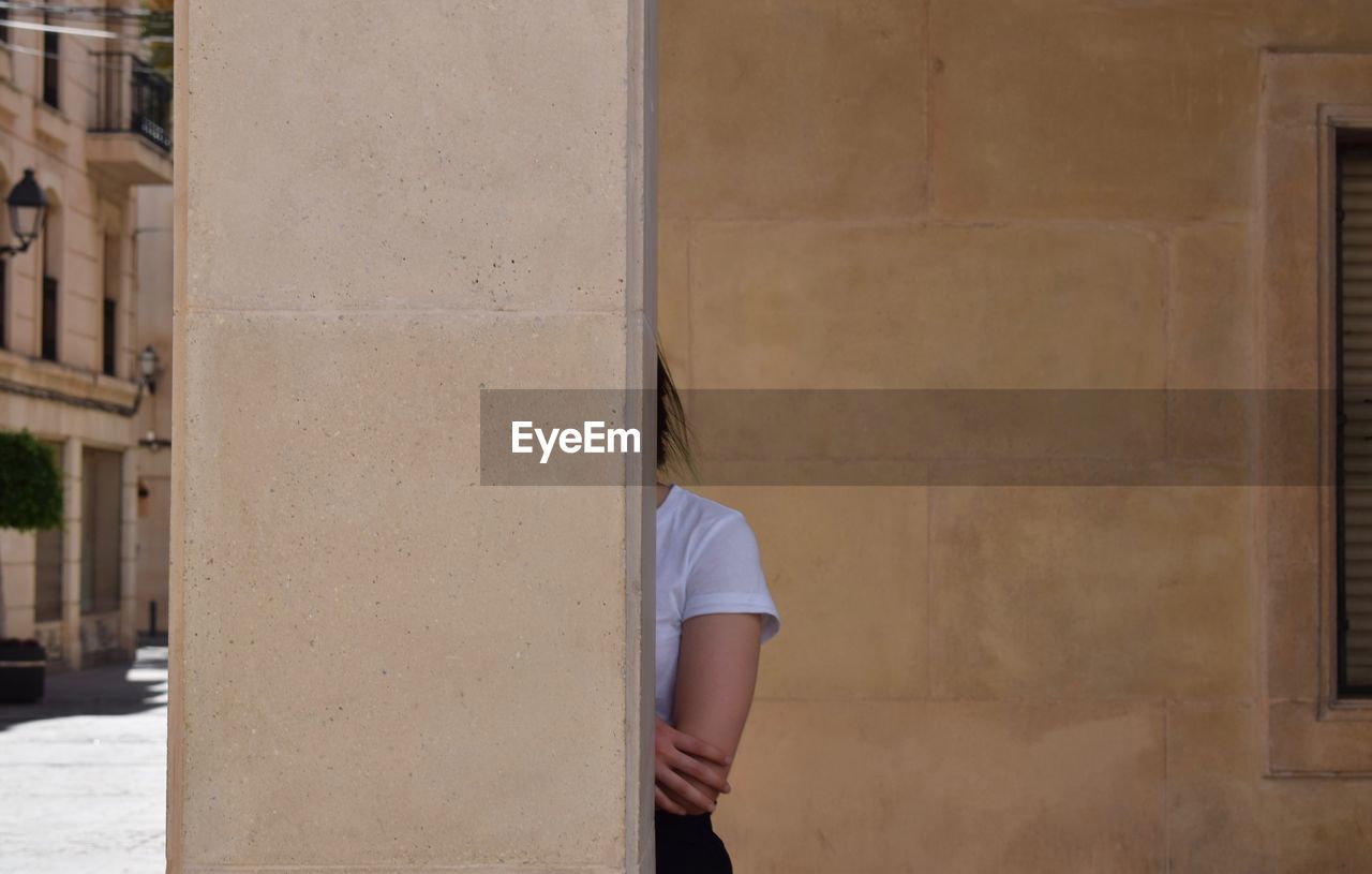 Woman hiding behind pillar